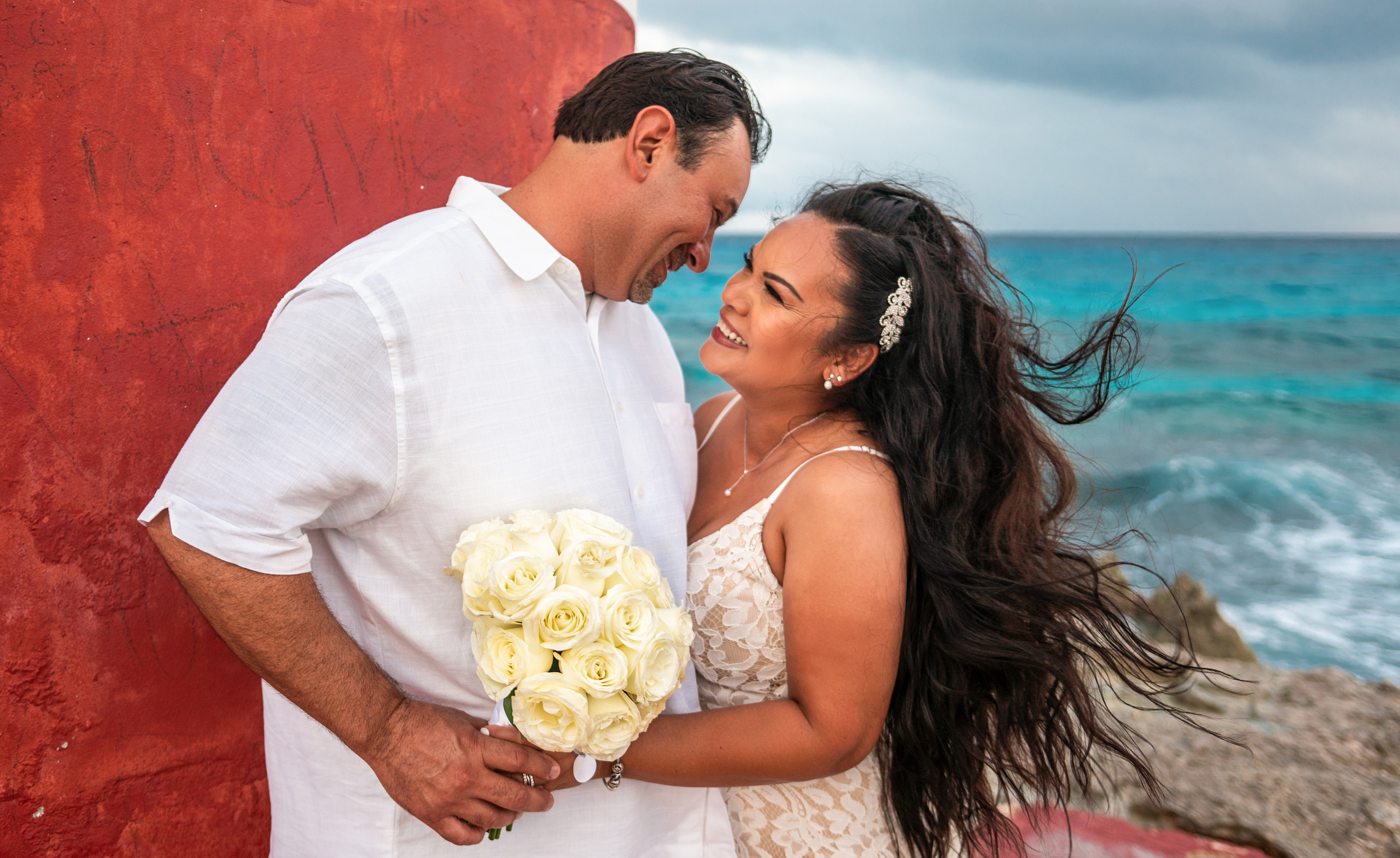 Romantic wedding photo by the ocean at Isla Mujeres lighthouse – adventurous couple session by Mexican photographer