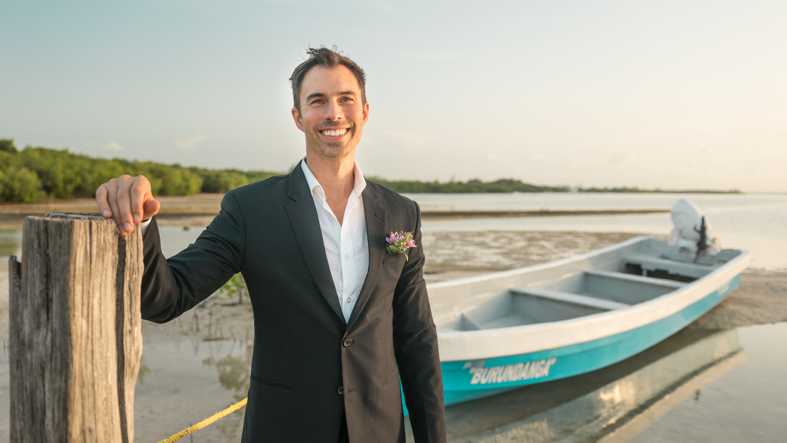 Sunset wedding photo with groom on fishing boat near shore – Riviera Maya