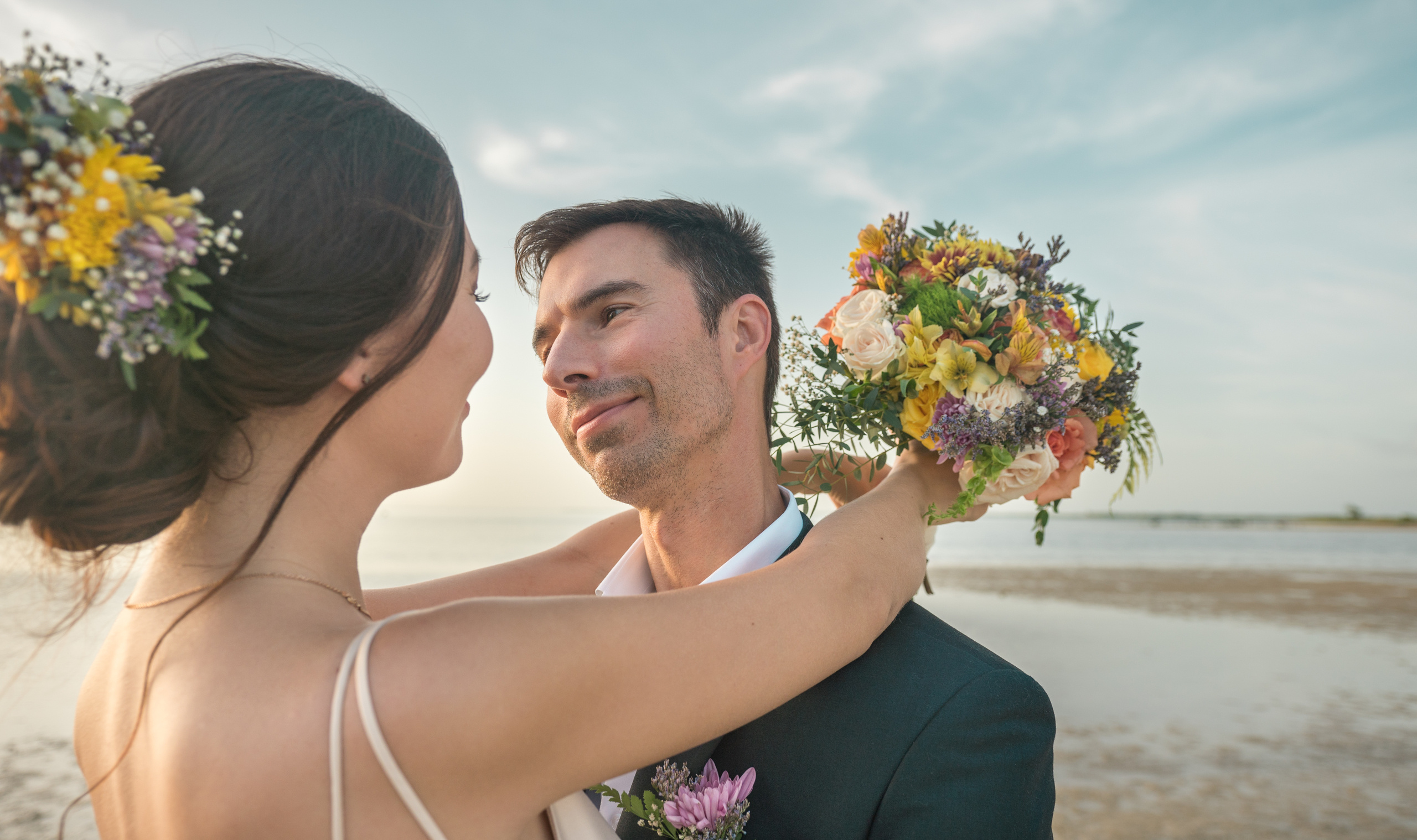 Tropical wedding photo with soft sky and ocean view – candid couple moment