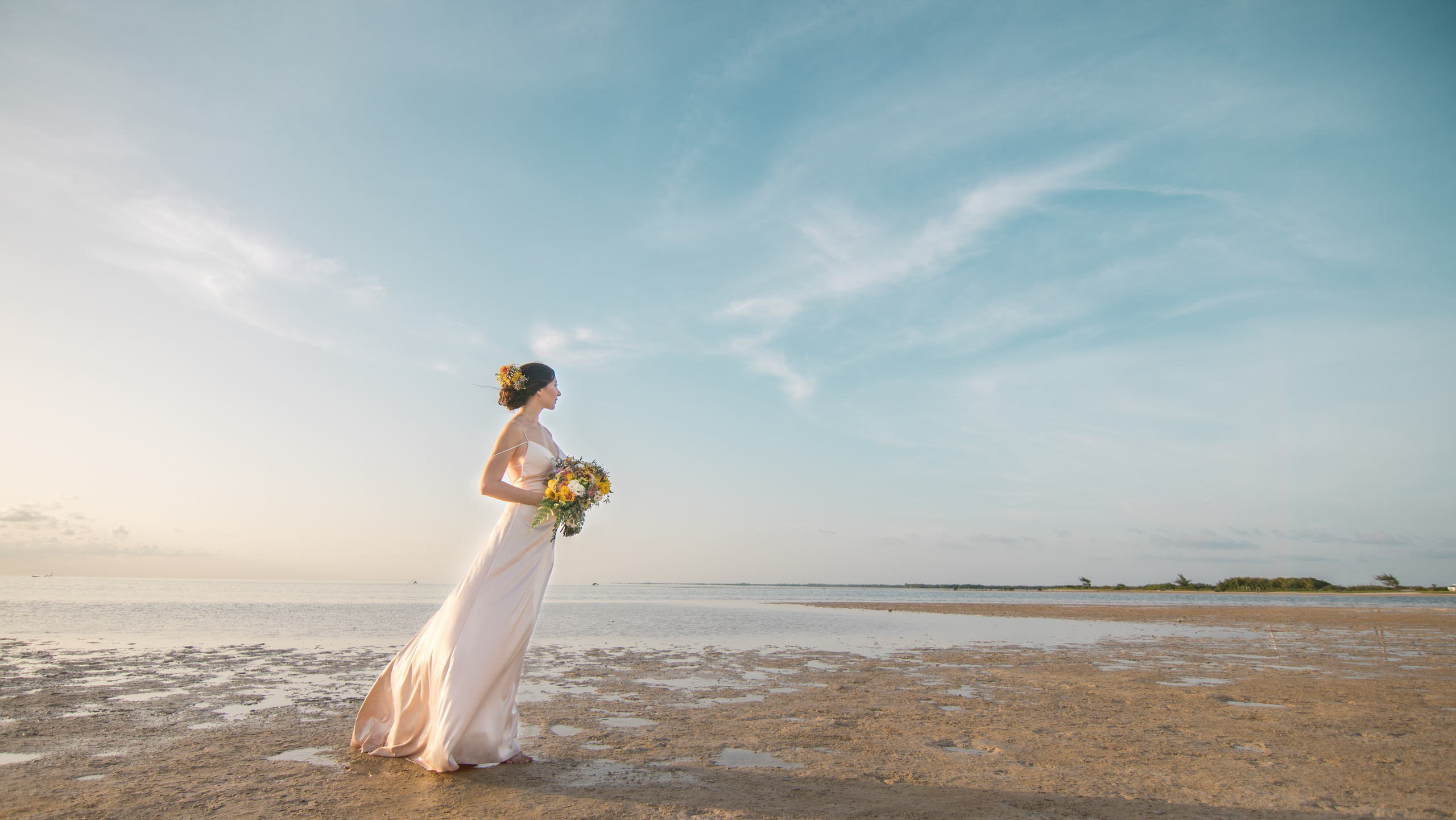 Bride embracing at low tide beach during golden hour in Mexico