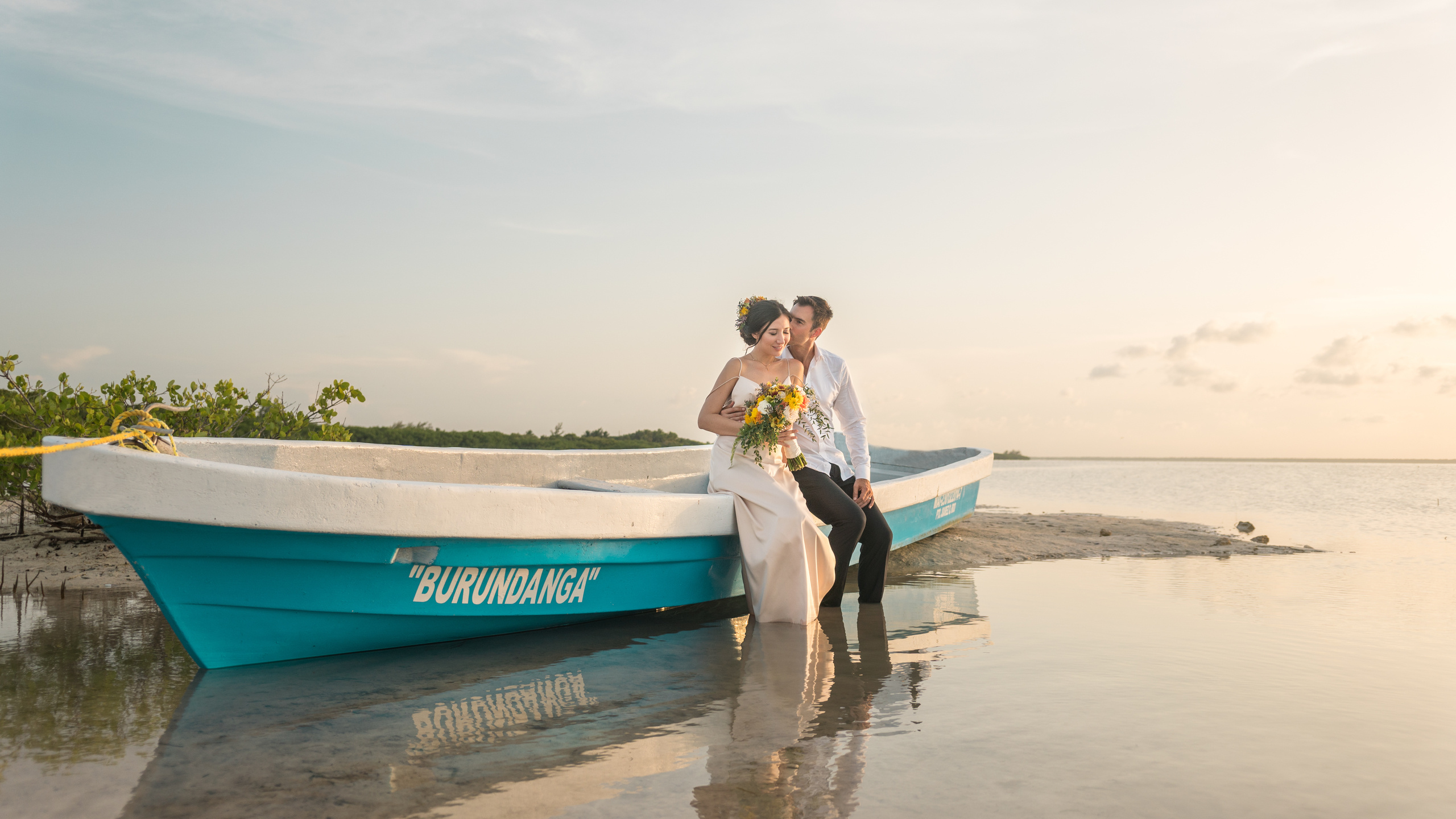 Intimate seaside wedding moment at golden hour with traditional Mexican boat