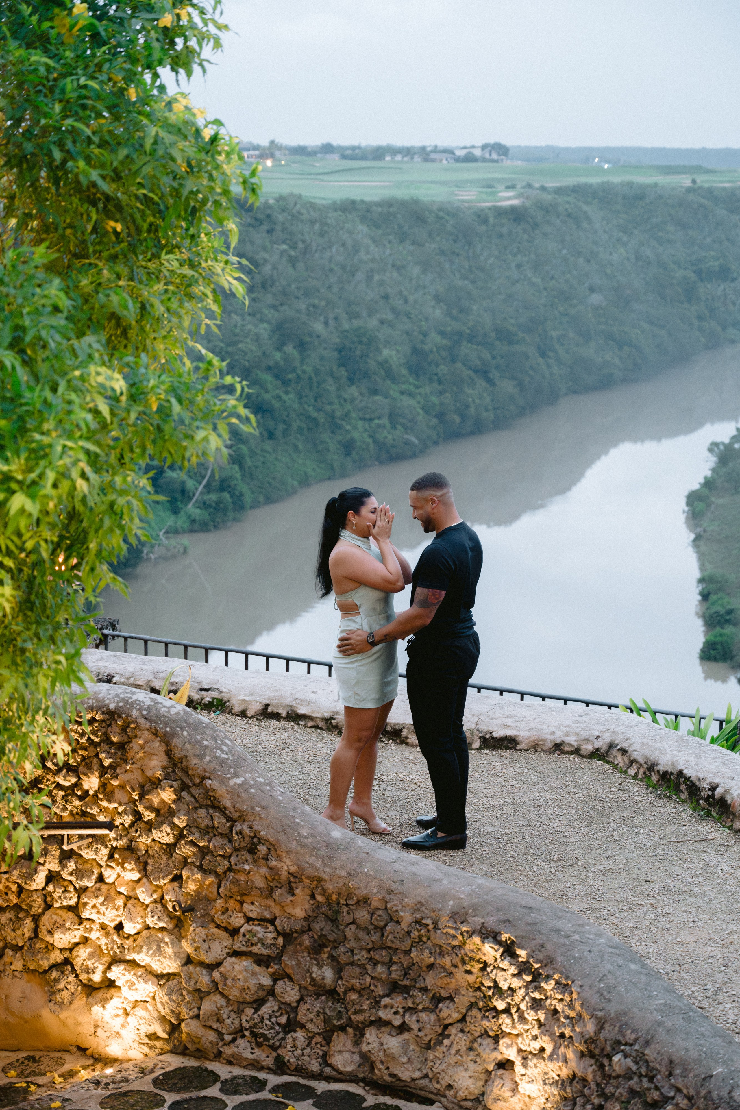 Man proposing to a woman at a scenic overlook with a river valley in the background, surrounded by rustic stone of Altos de chavon. Punta cana wedding family fashion photographer dominican republic, destination wedding photographer, elopement photography Punta Cana