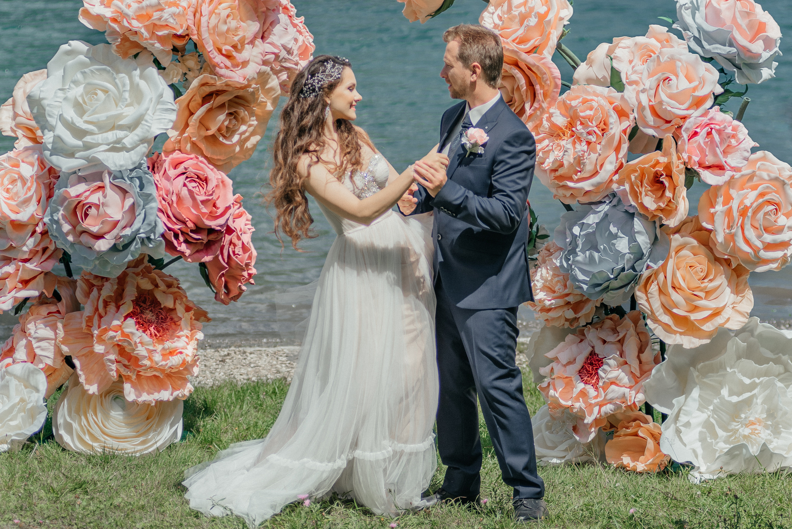 A happy dancing wedding couple in flowers on the swiss lake in the mountains. Switzerland