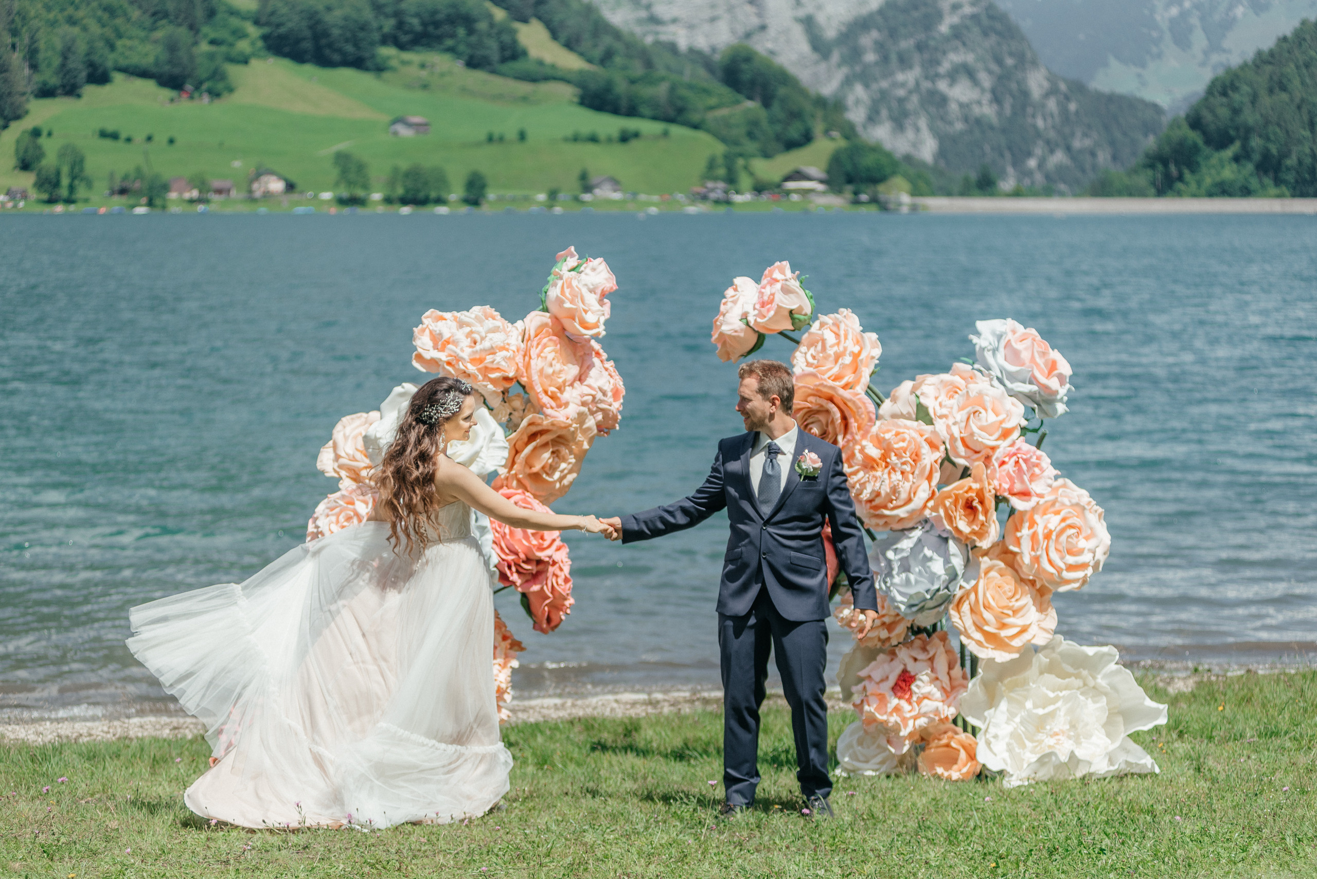 A happy dancing wedding couple in flowers on the swiss lake in the mountains. Switzerland