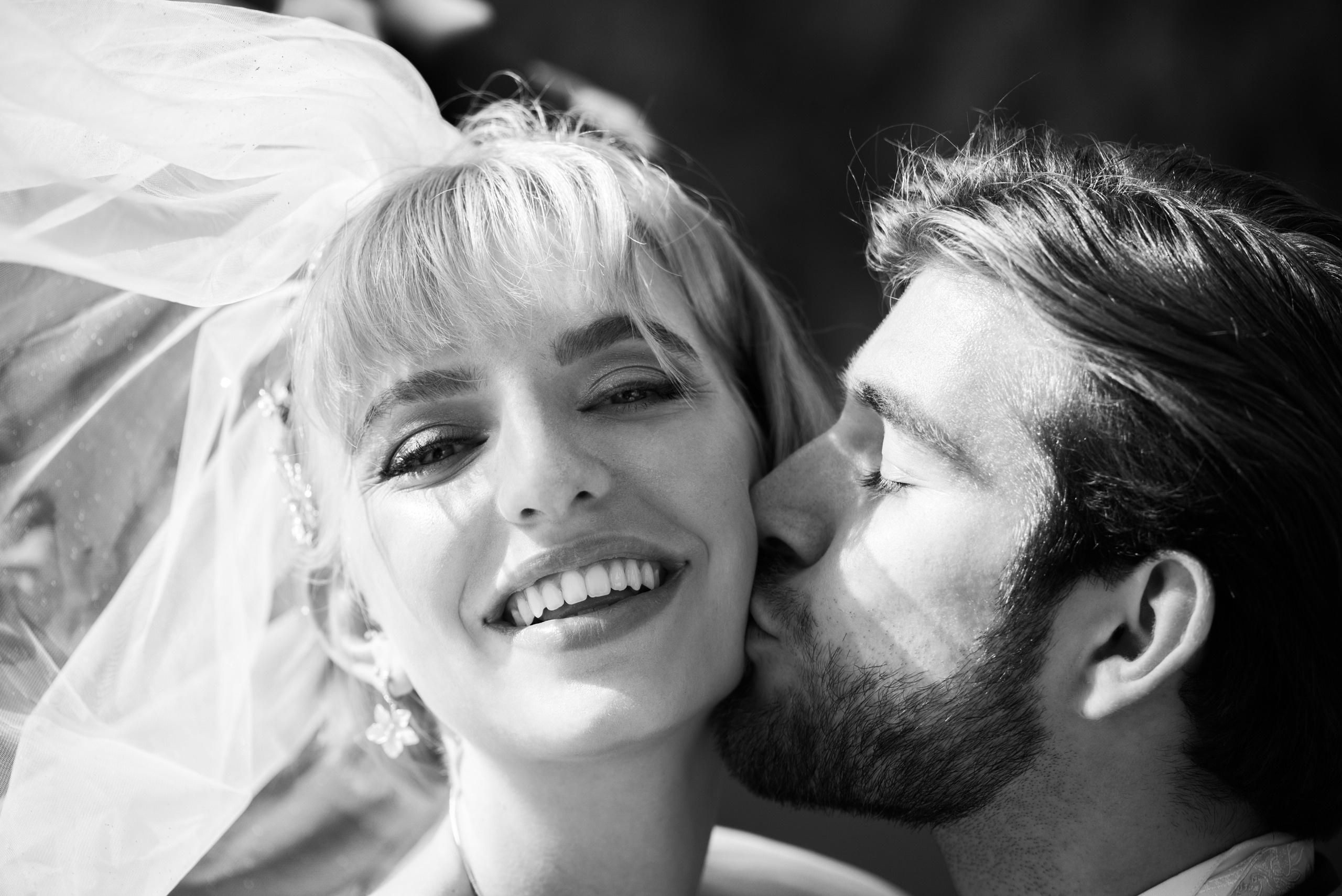 A fiance is kissing his happy and beautiful bride. A happy wedding couple in Switzerland. Black and white photography
