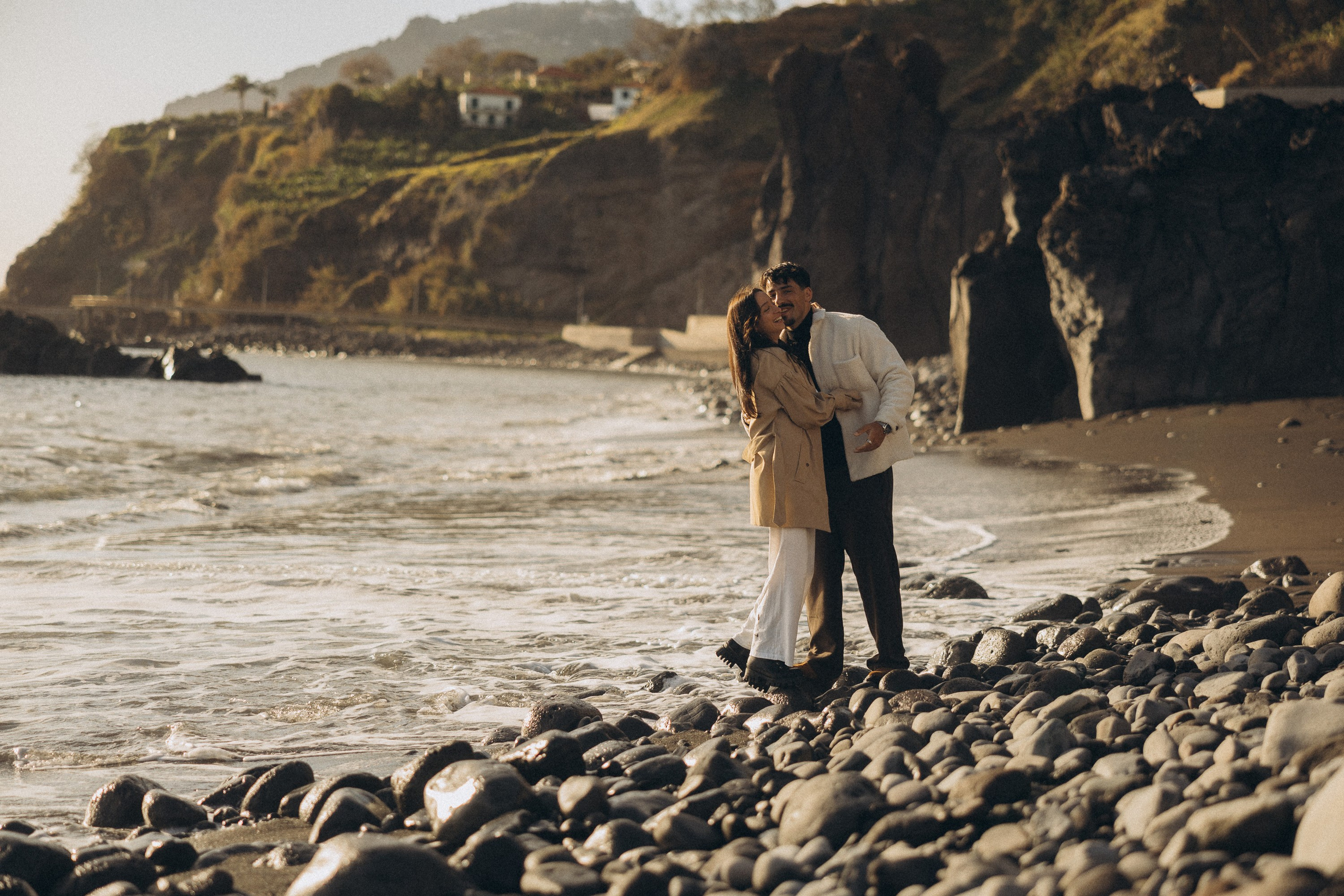 Couple sharing a romantic moment during sunset on Madeira Island, with the ocean and cliffs in the background