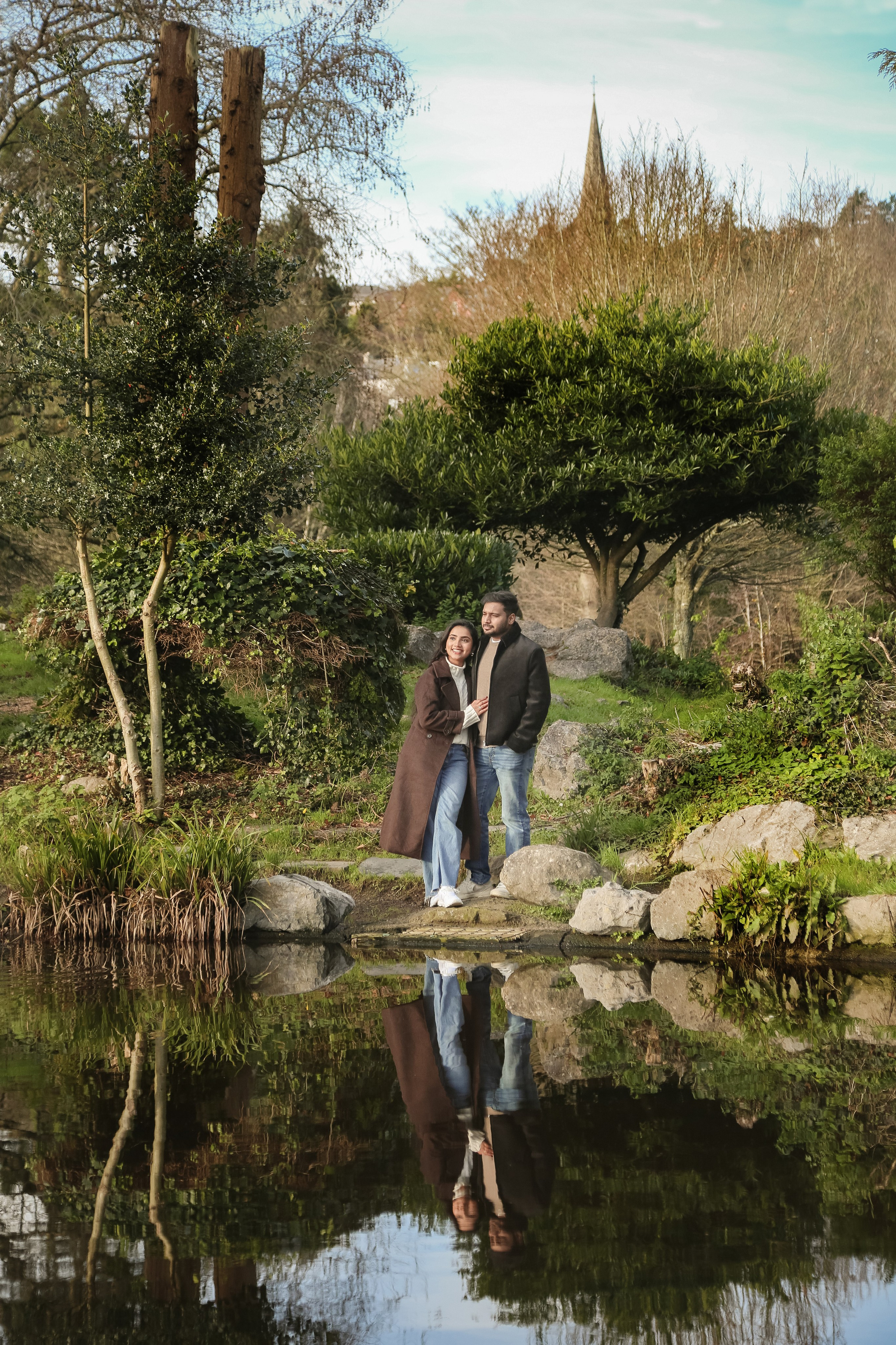 A calm and intimate moment beside still water, surrounded by greenery and soft reflections that mirror connection and ease.