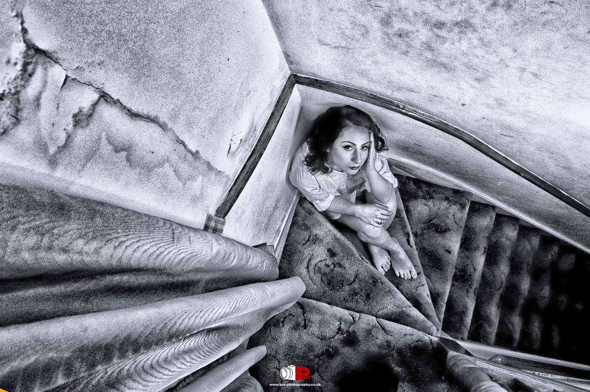 A contemplative woman sitting on a worn staircase in a powerful monochrome artistic shot.