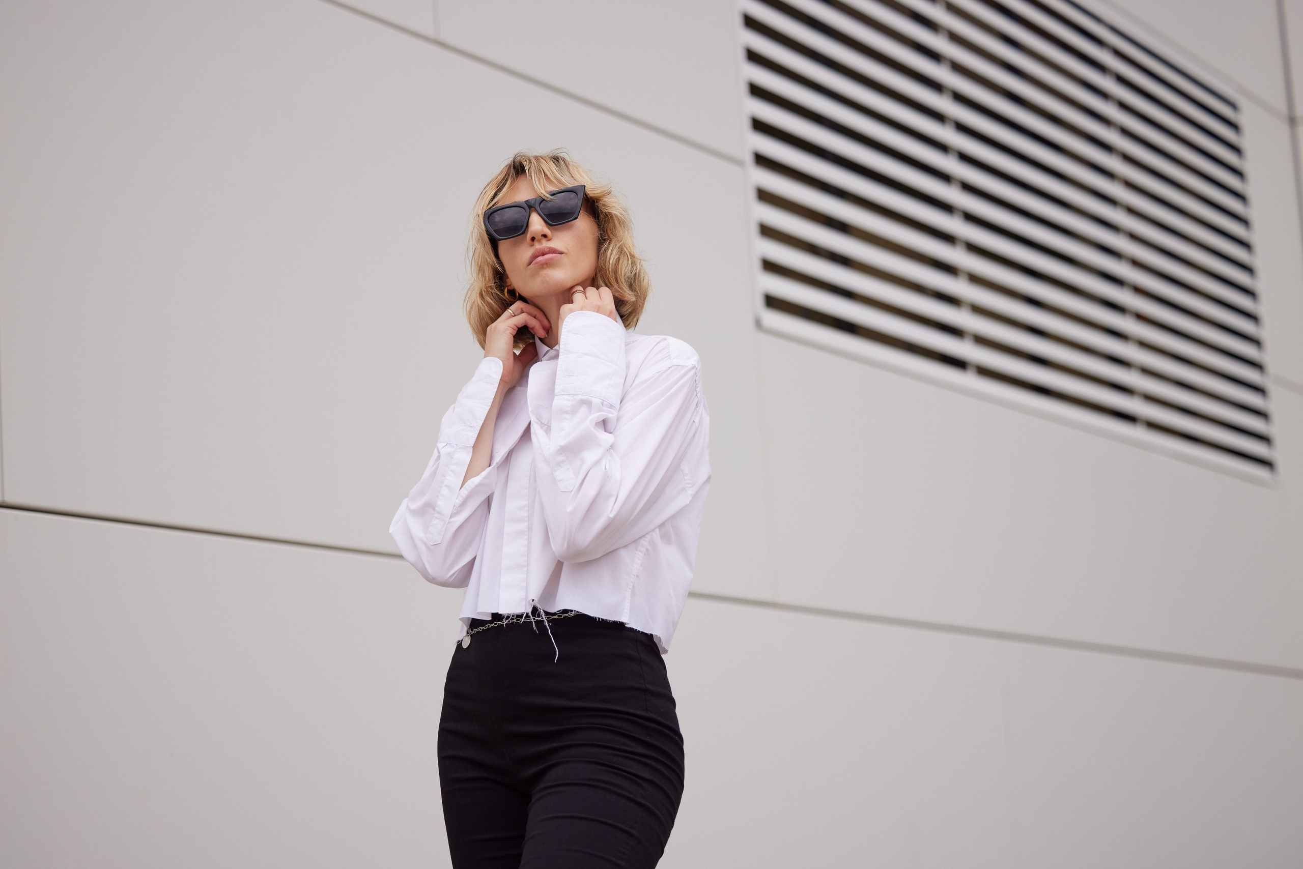 Location portrait of a young woman in sunglasses against the backdrop of a building - photographer Andrey Dunin