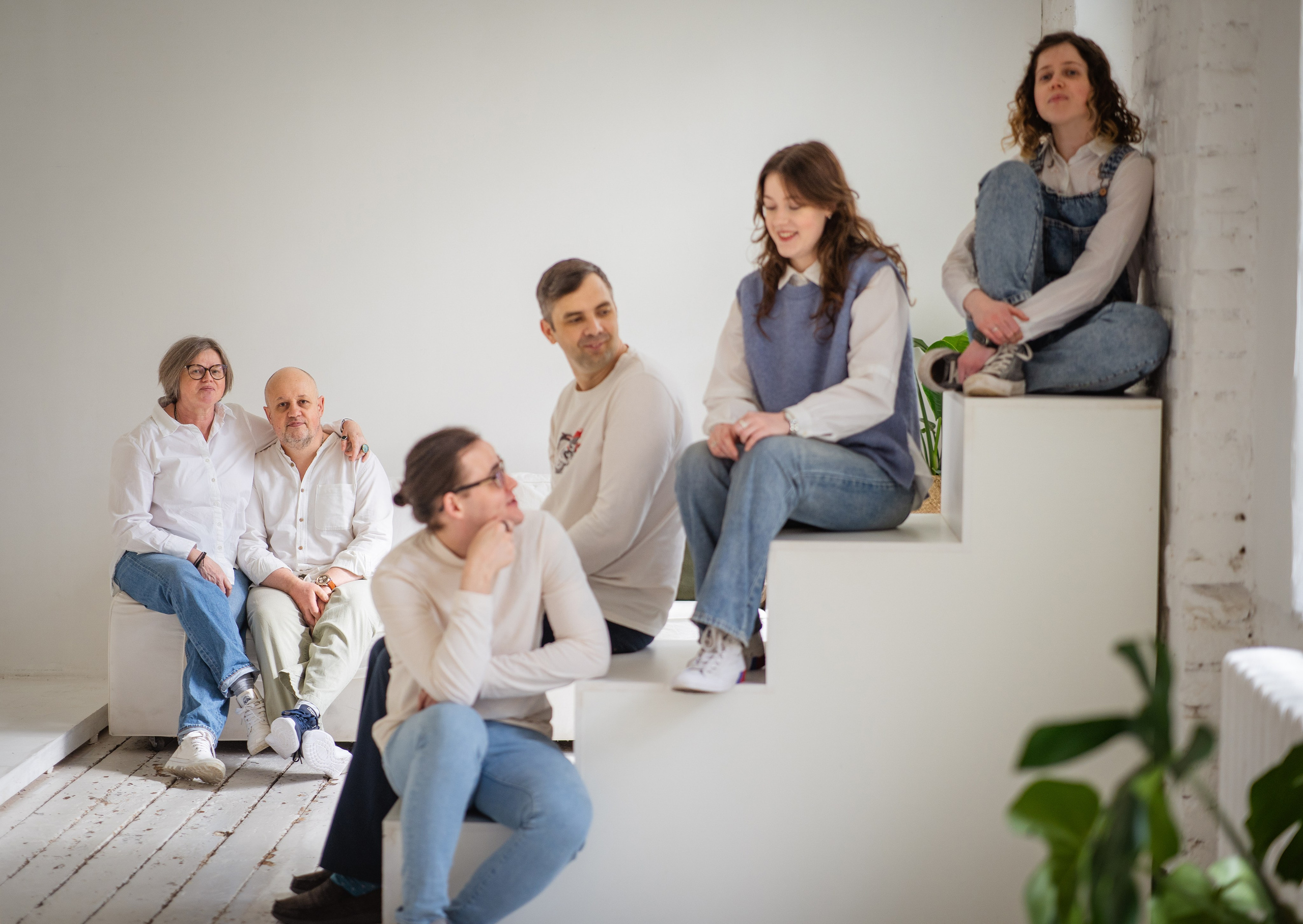A beautiful family in the photo studio with a white interior, all dressed in denim. Riga family photographer