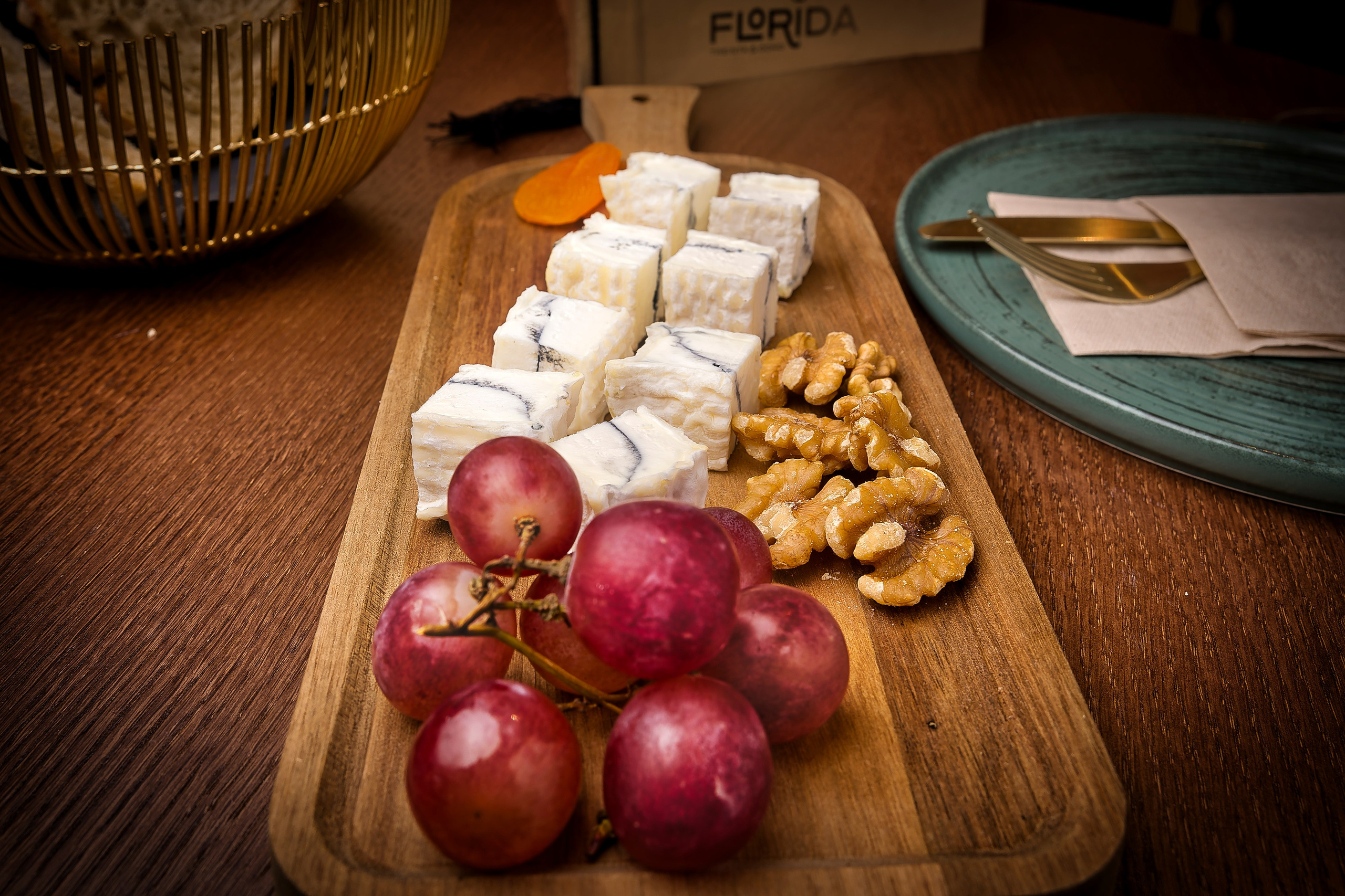 Fotografía gastronómica de tabla de quesos artesanales con frutas y frutos secos, composición elegante para restaurante o catering gourmet. queso con nueces y uvas rojas