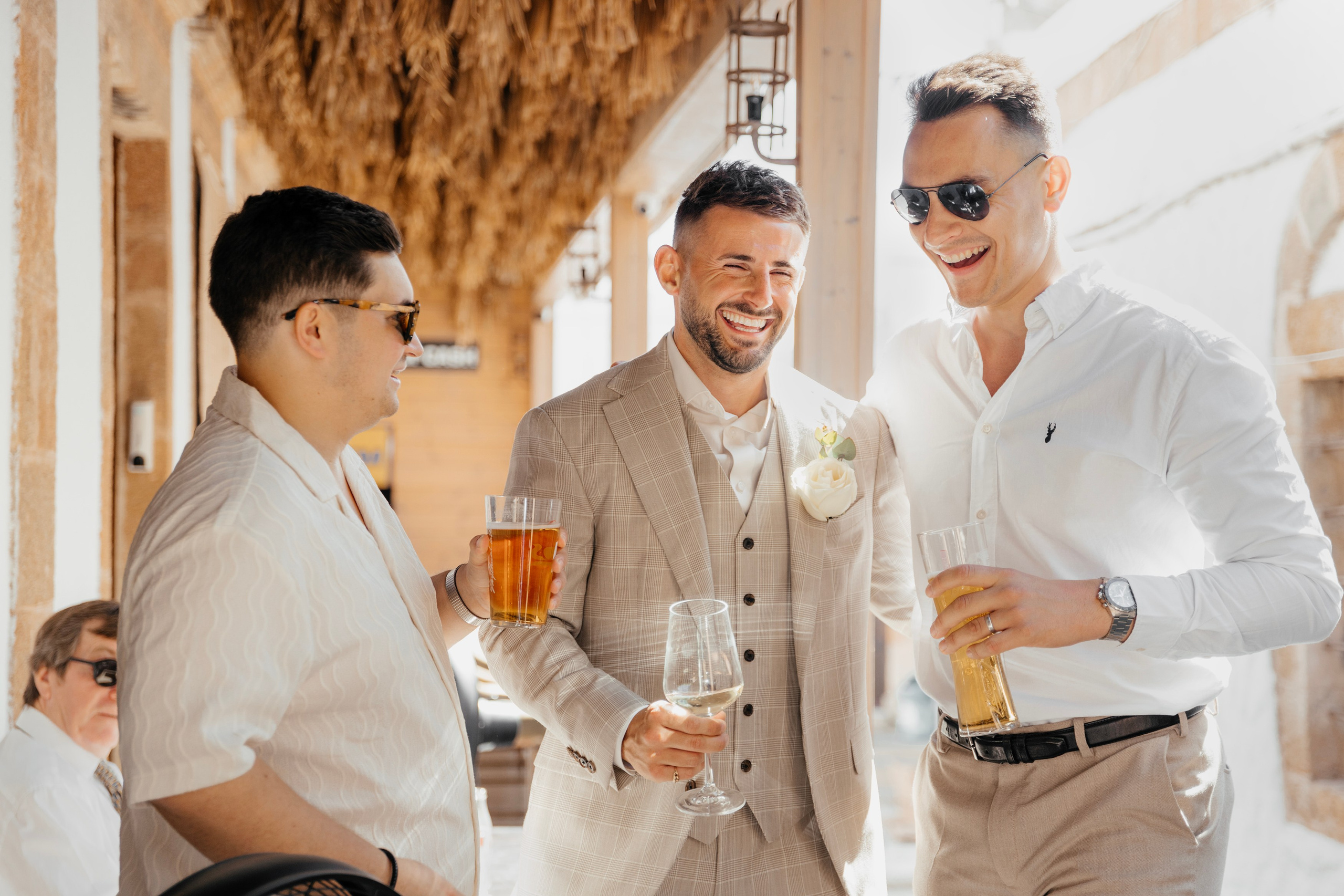 Groom and his friends celebrating at a lively pre-wedding party in a cozy bar in Lindos, Greece