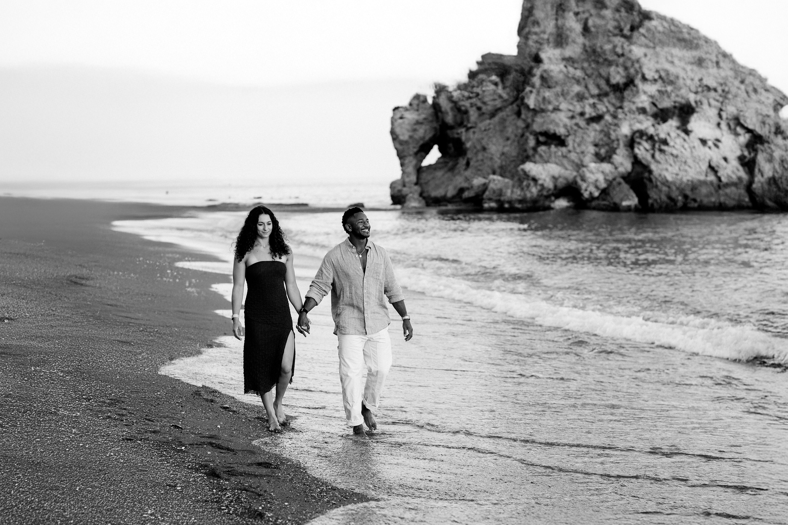 Newly engaged couple walking hand in hand along a Málaga beach after a romantic seaside proposal. Destination engagement session on Spain’s Costa del Sol capturing natural movement and ocean views.
