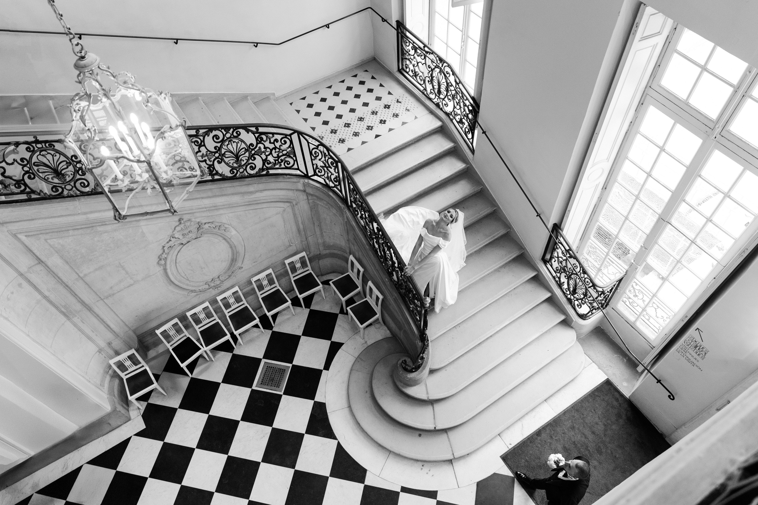 Bride descending a grand Parisian staircase in a historic building, luxury editorial wedding photography in Paris, black and white