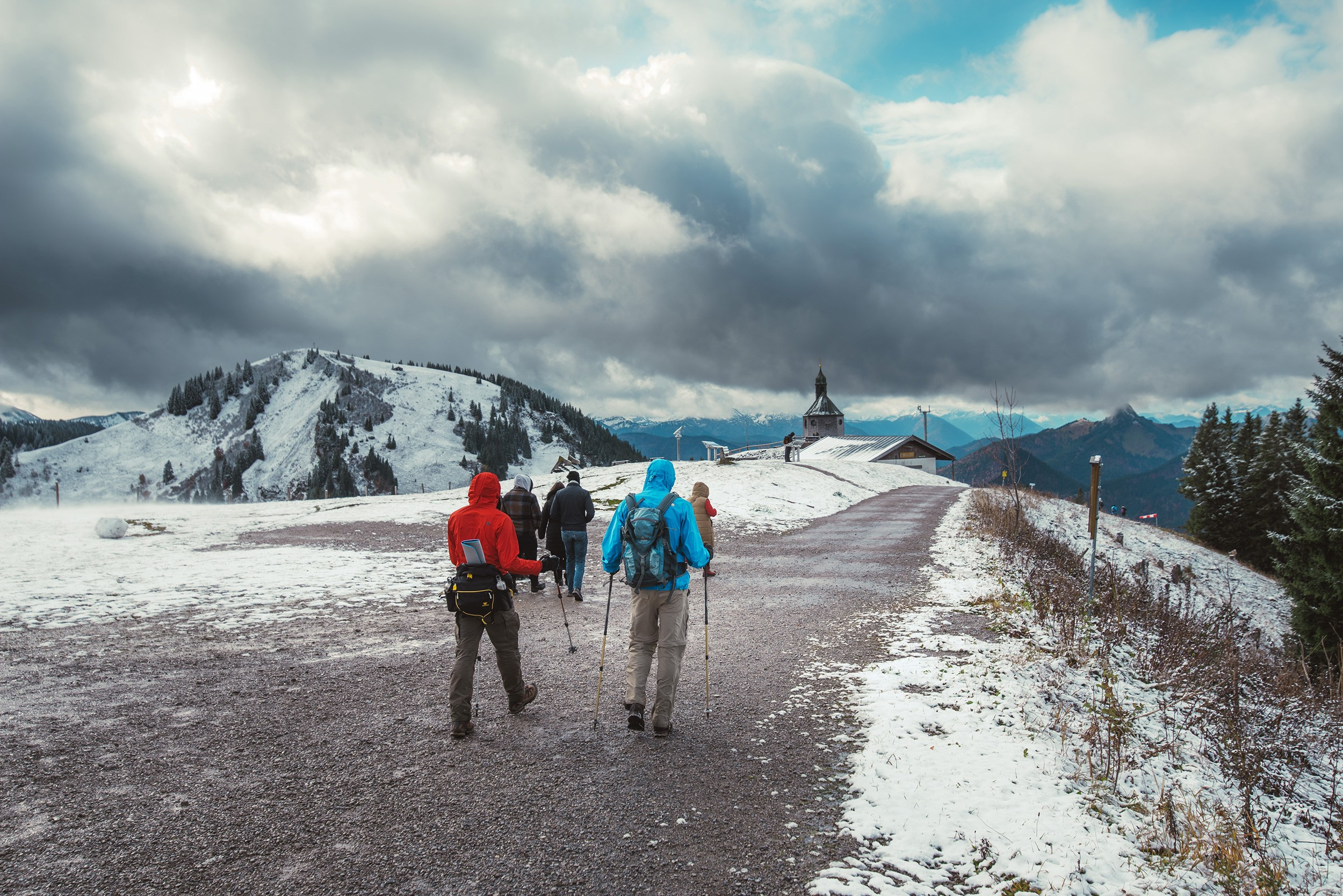 Hikers walking along a snow-covered trail towards the summit of Mount Wallberg.