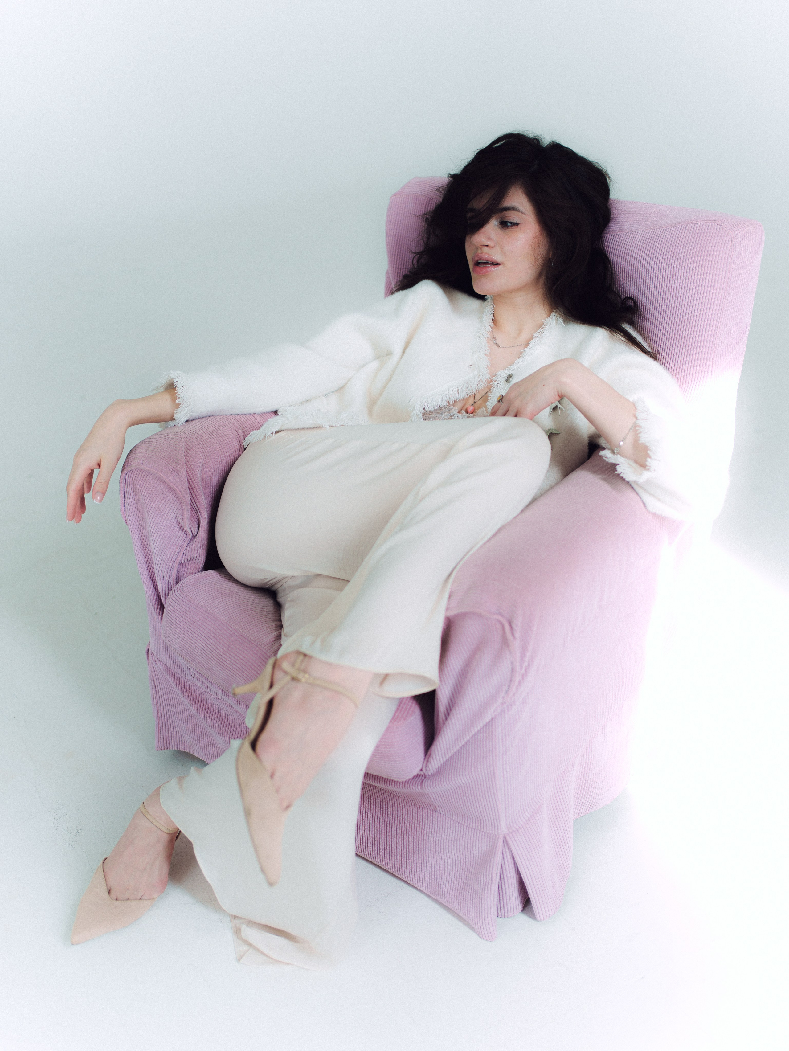 Woman lounging in a pastel chair in bright soft studio