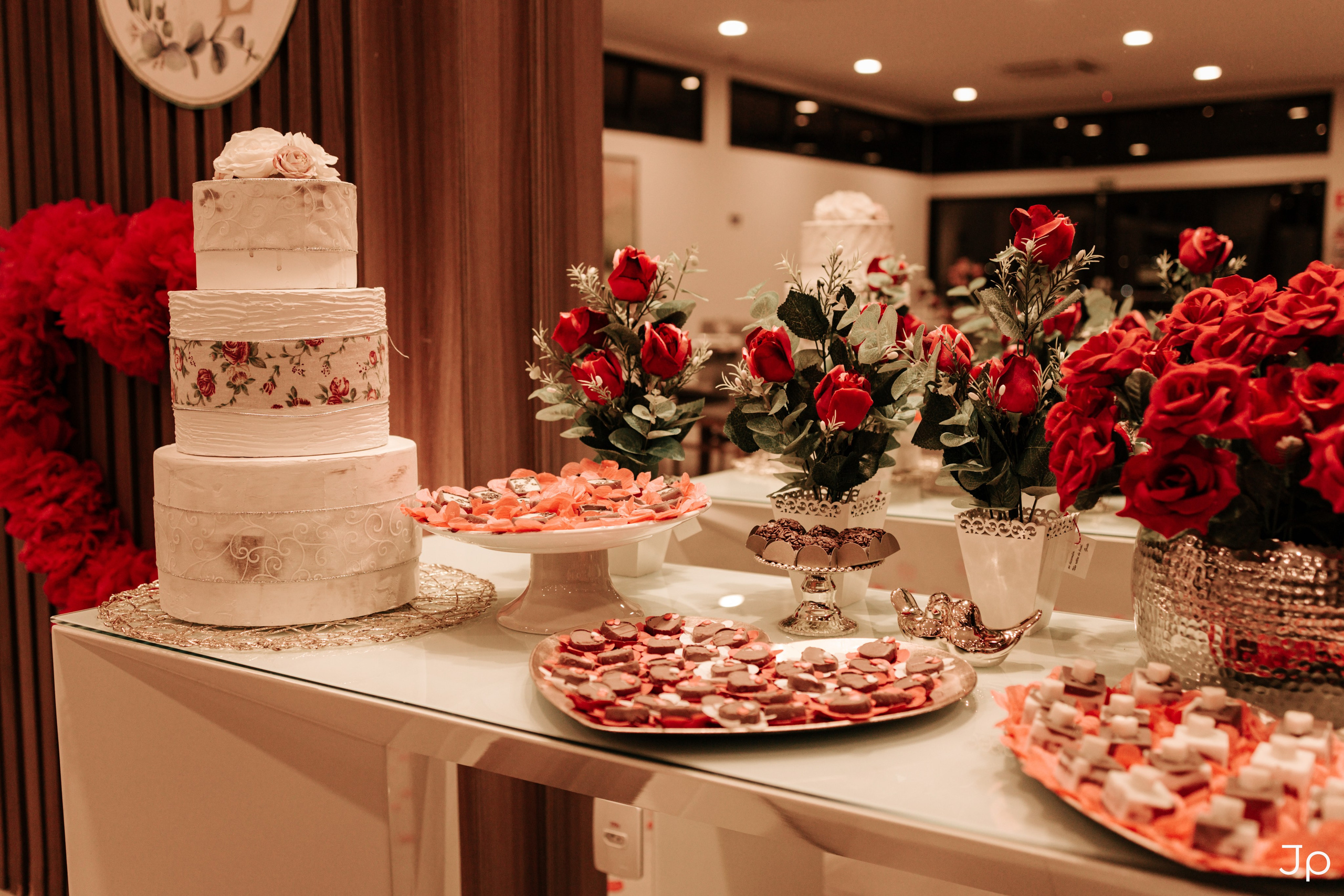 Mesa decorada com flores, doces e bolo de noivado.