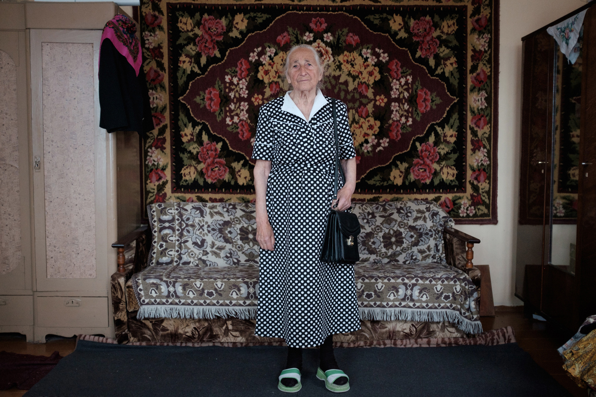 Vera is standing in a polka-dot dress. The fabric was bought by her sister Galina in France. In a Soviet Union's time was difficult to  buy a beautiful fabric or dress. That's why people were inclined to sew dresses and also was difficult to find fabric like this. It was a time of deficit. Not all group of people had access to the shops where you could buy deficit goods. 
