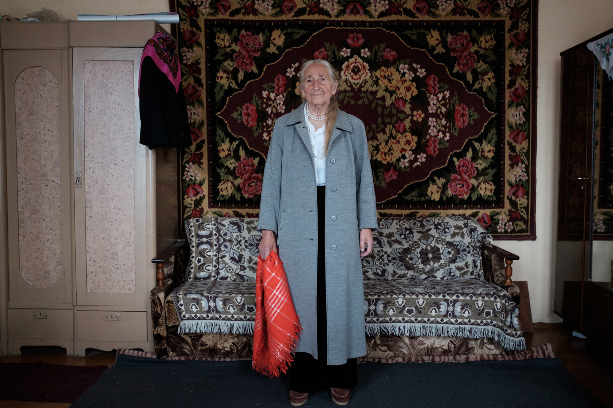 Vera is posing in a gray coat that her daughter worn during her first year at the university in Minsk.