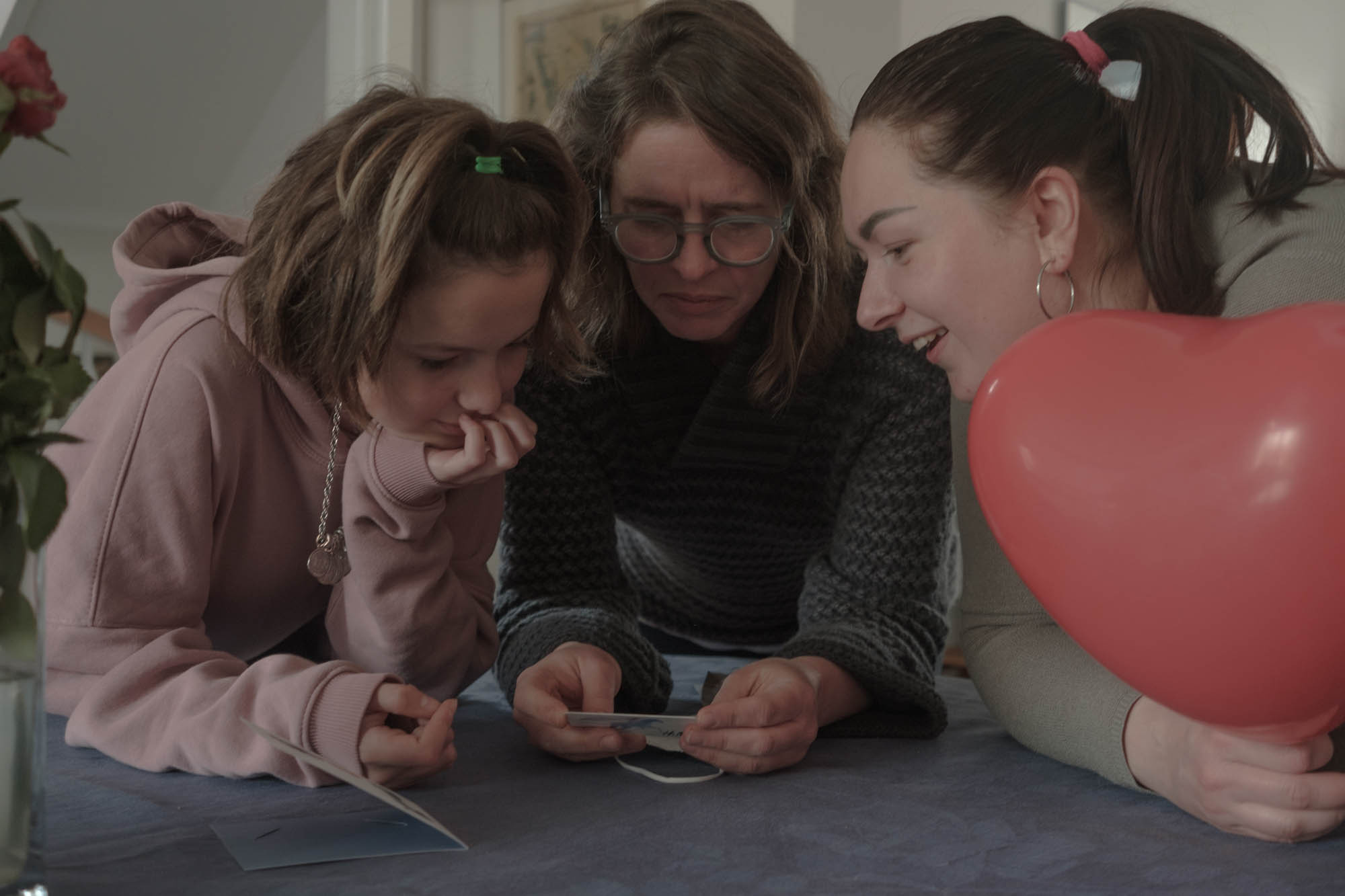 Julia helps to read the information of the certificate from H&M giving as a gift to Sabrina from people in Germany. Liliya is holding a balloon.  