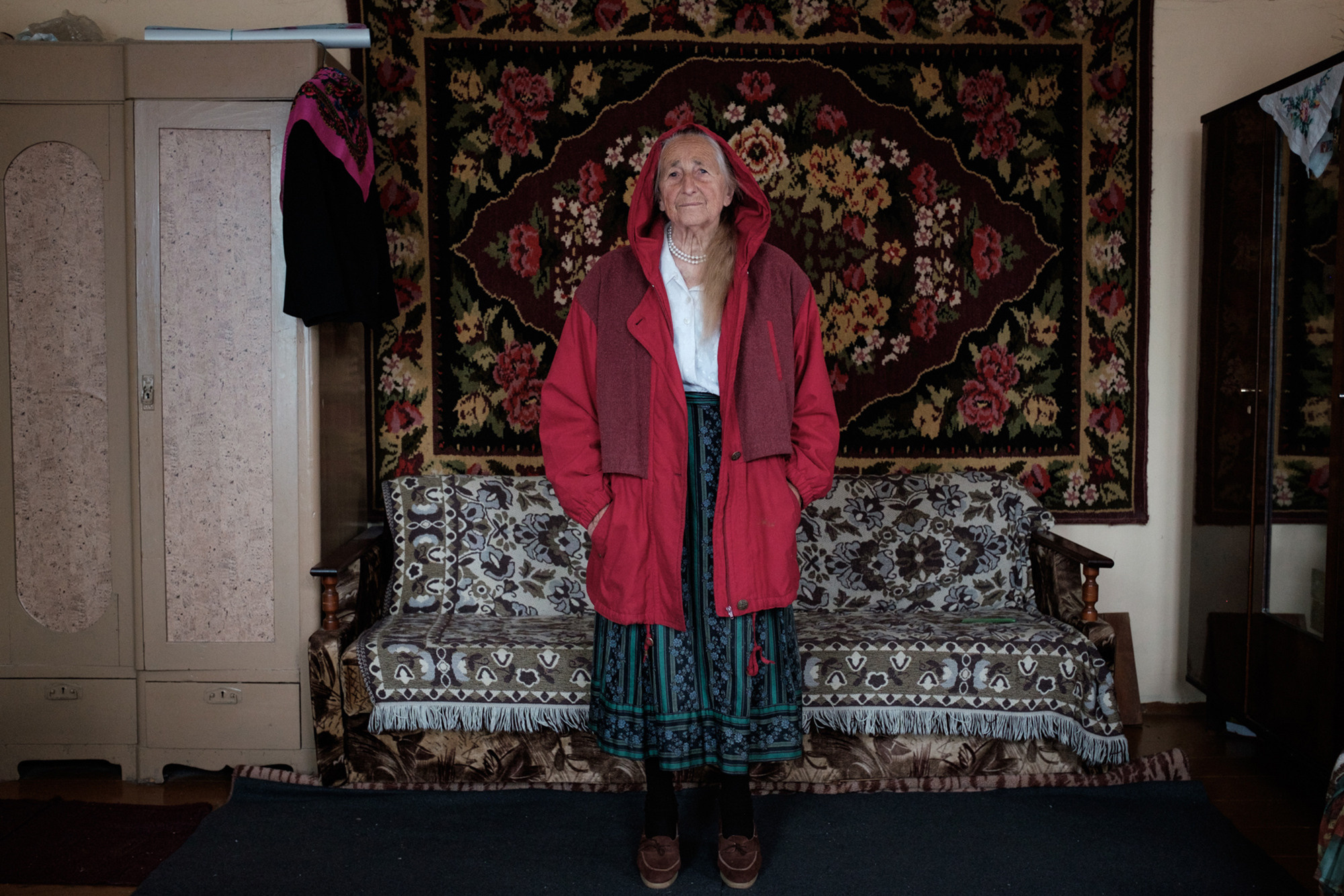 Vera is posing in a red jacket which her daughter-in-law gave her when Vera came back from a hospital after a tumor on Vera's arm had been operated.