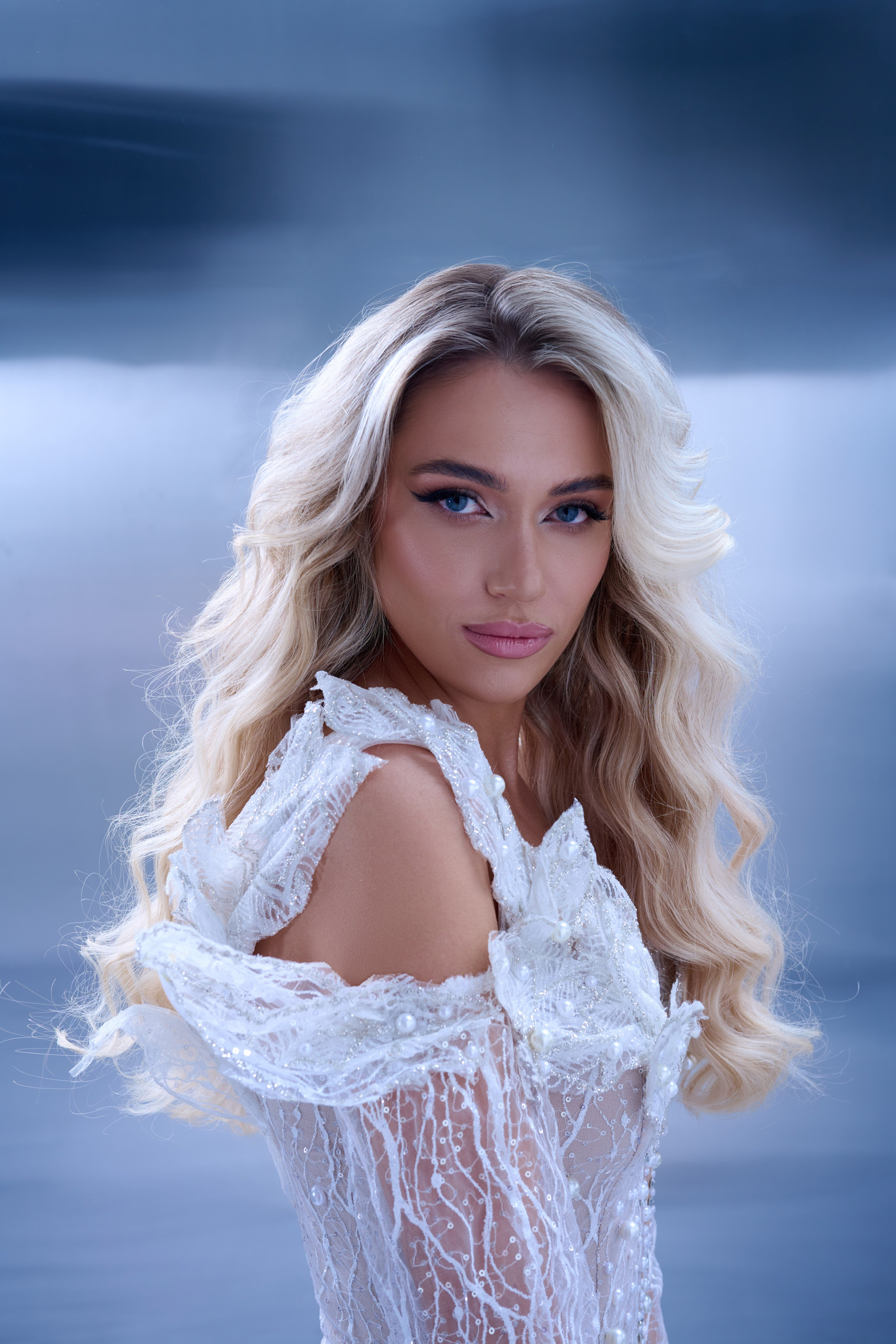 High-fashion portrait of woman wearing white sequin couture dress with dynamic wind lighting