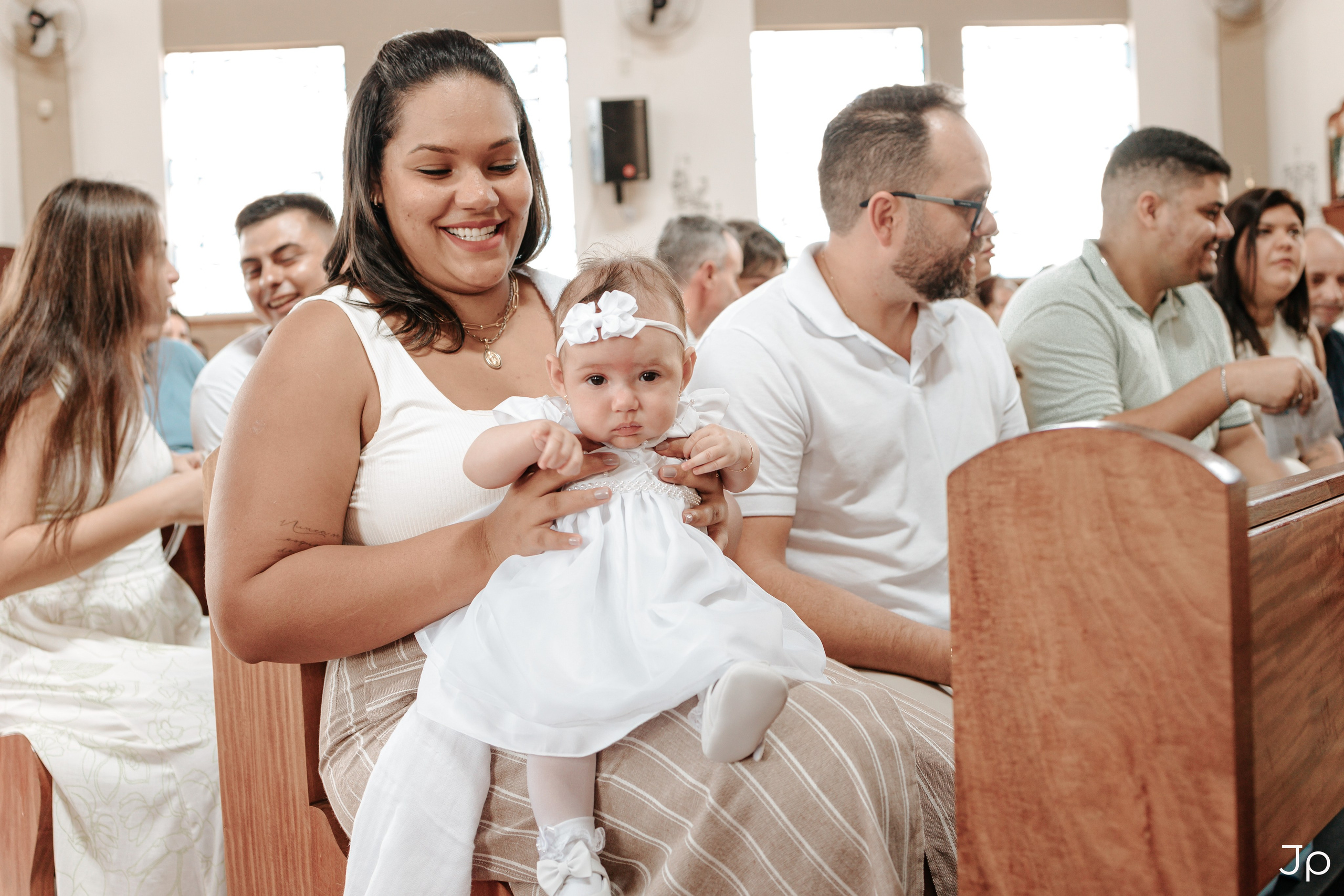Família reunida no banco da igreja, sorrindo.