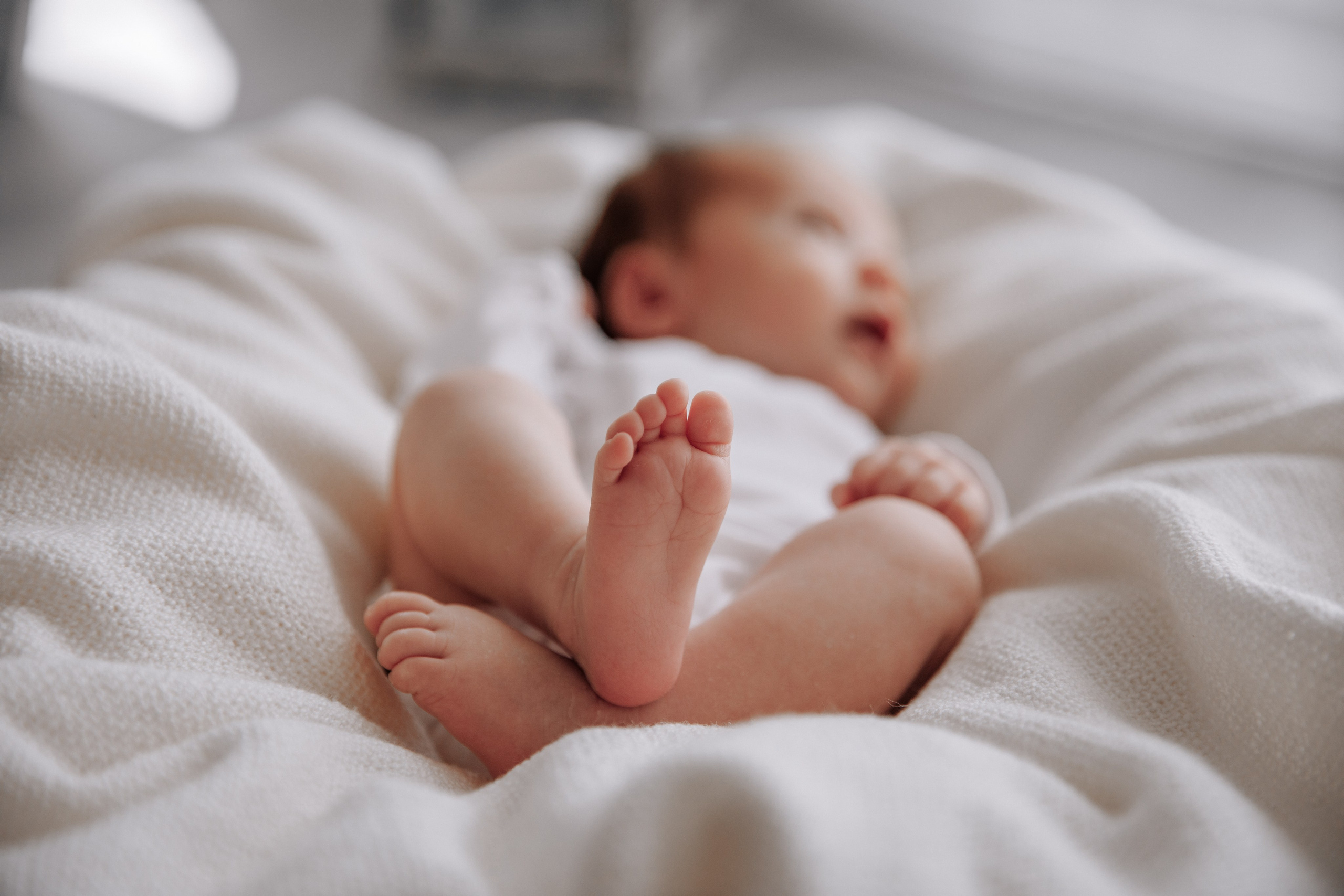 Kleine Babyfüße liegen in geflochtenem Korb während Fotoshooting.