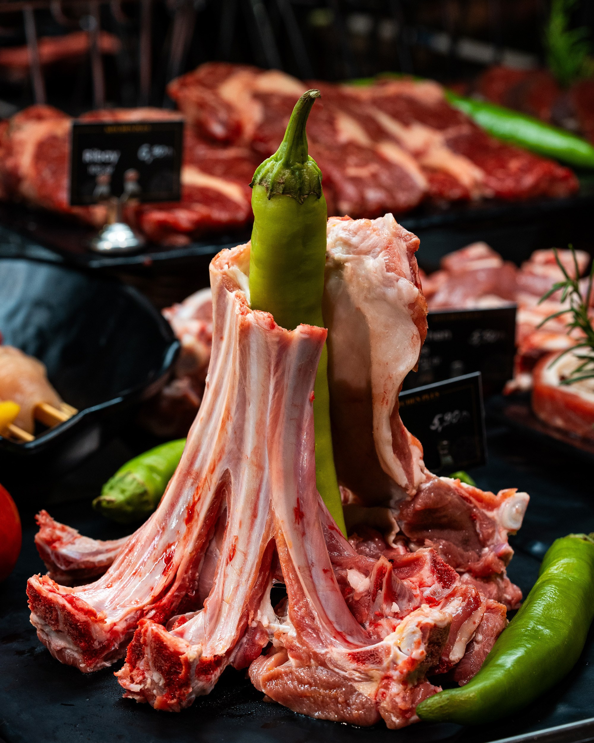 Bir göyərtilmiş yaşıl bibərin ətrafında qurulmuş təzə quzu qabırğaları (lamb chops/racks), qəssab dükanının vitrinində.
