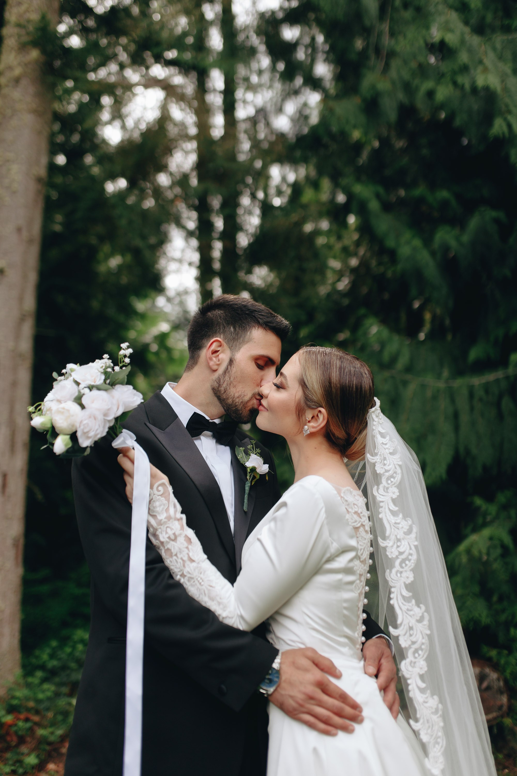 Bride and groom kissing in forest, wedding ceremony moment