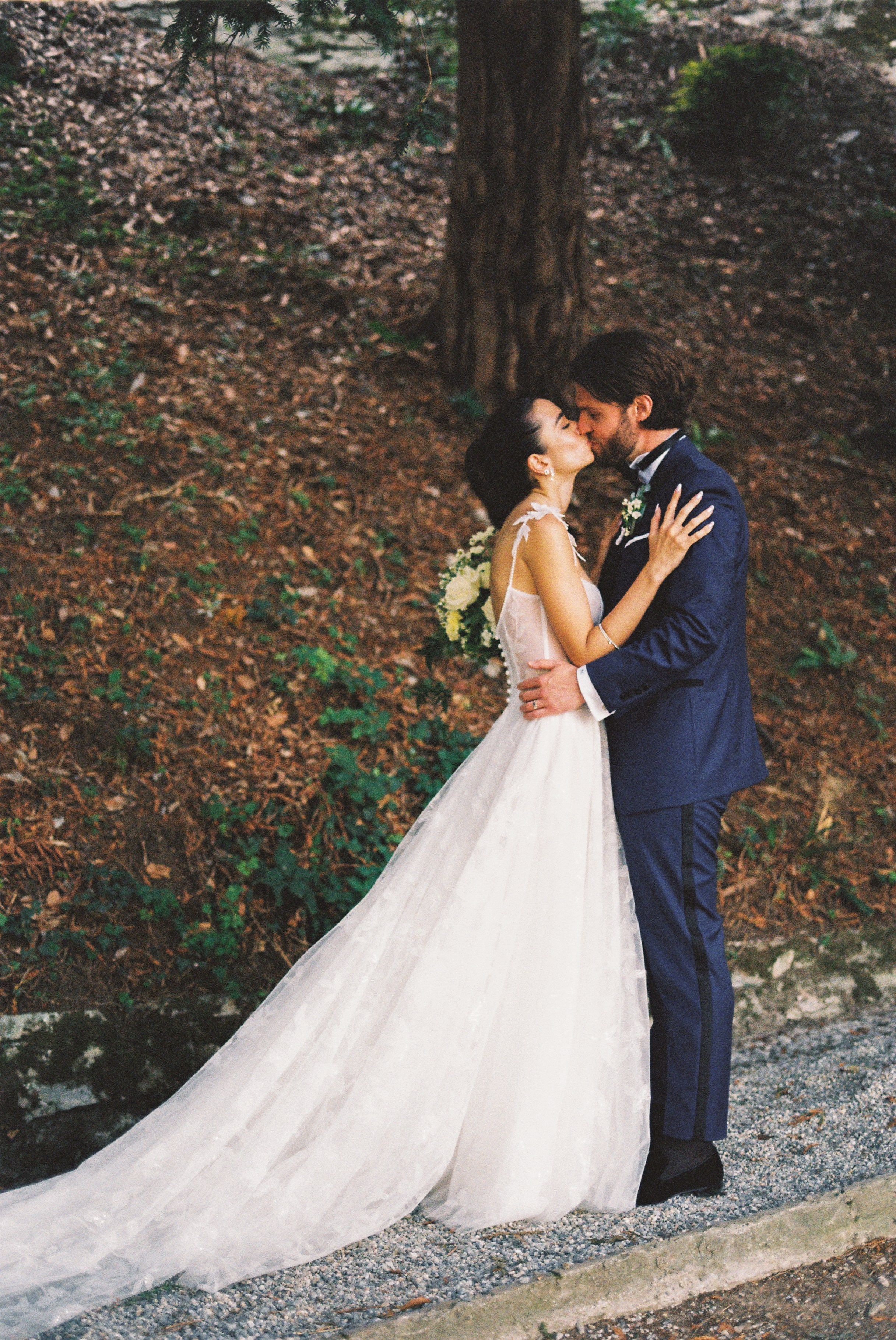 Bride and groom share a kiss in a wooded outdoor setting after the ceremony.