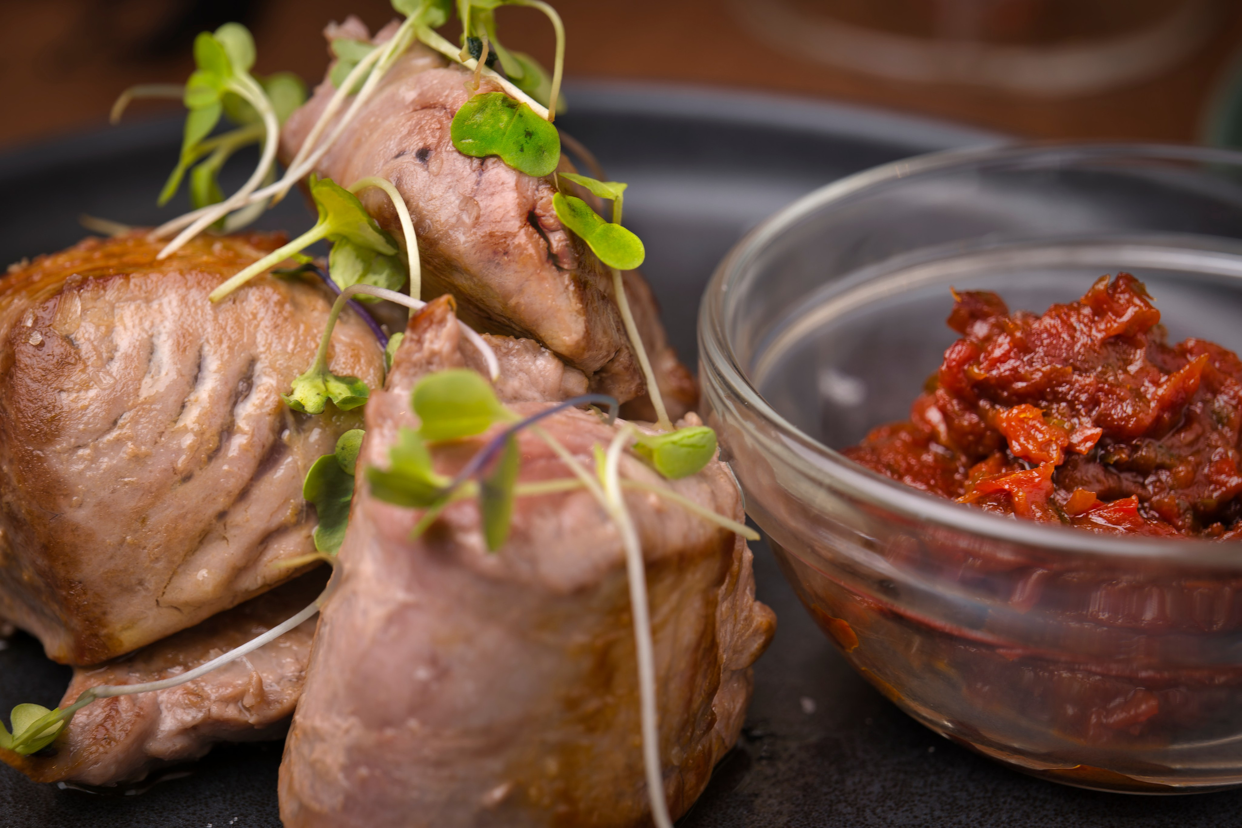 Imagen de comida cuidadosamente emplatada sobre fondo oscuro, capturando detalles y contraste visual.