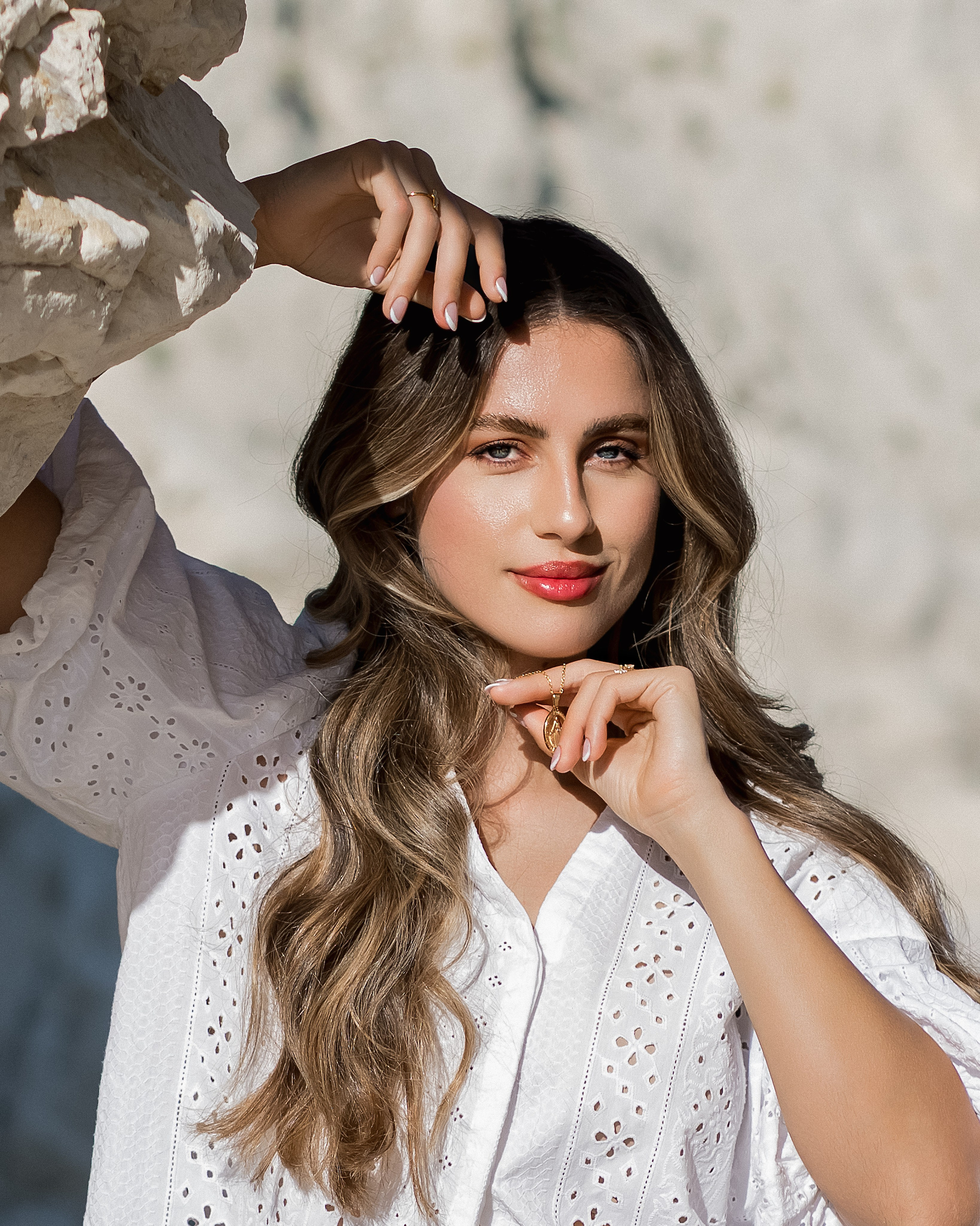 Sesión de retrato femenino en Valencia, España, con una mujer de largo cabello suelto posando bajo suave luz natural frente a una pared de piedra texturizada. Este elegante retrato en primer plano captura la belleza, la confianza y las emociones auténticas con un refinado estilo editorial, ideal para fotografía de retrato femenino, sesiones individuales, retratos inspirados en la moda, sesiones lifestyle y fotografía de marca personal en Valencia y toda España.