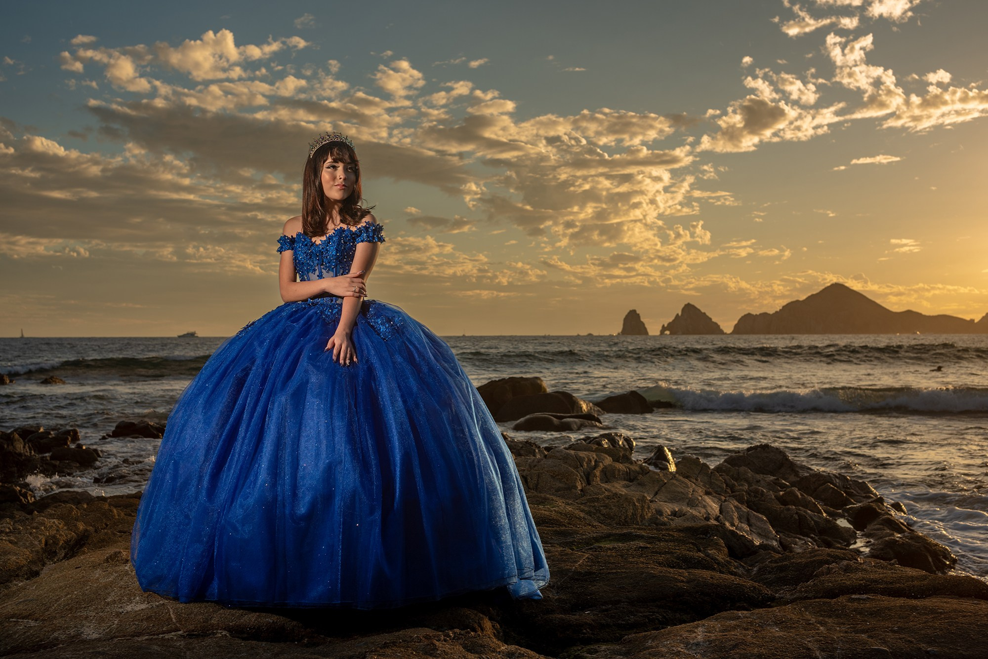Quinceañera photography in Los Cabos – Michelle posing in full-length blue embroidered dress on the beach at sunset, destination XV photoshoot Cabo San Lucas, elegant sweet fifteen portraits by the ocean