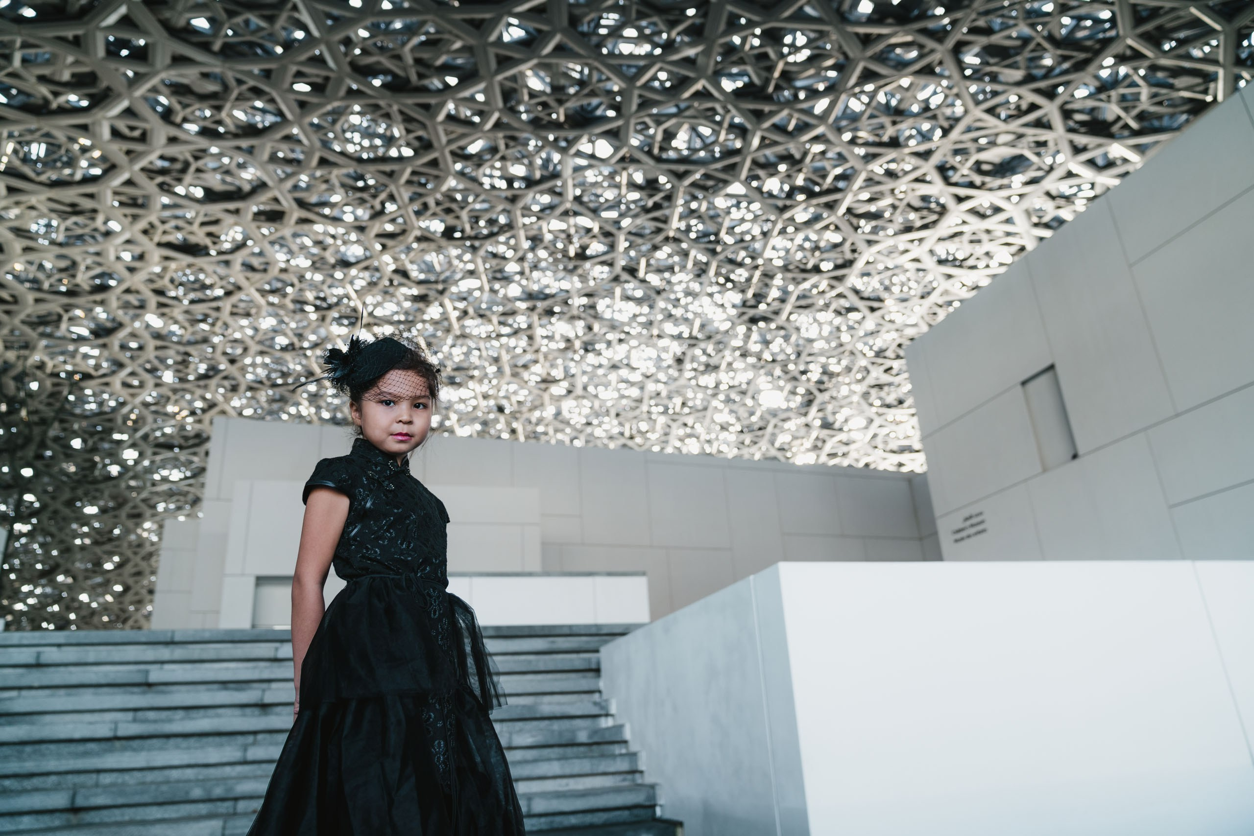 Girl dressed in a stylish black dress posing at Louvre of Abu Dhabi