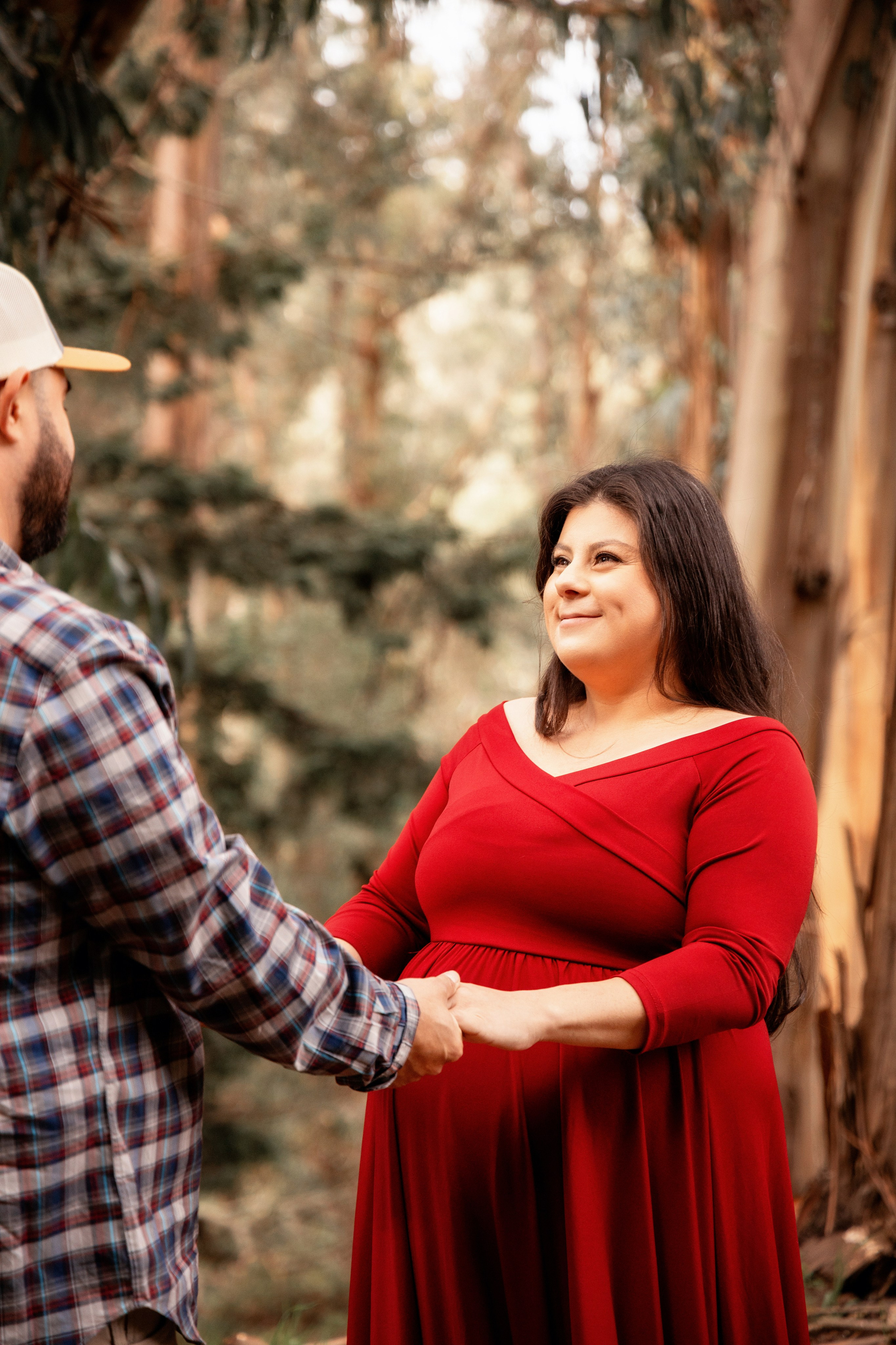 Tender portrait of a pregnant woman in the forest with sunlight filtering through