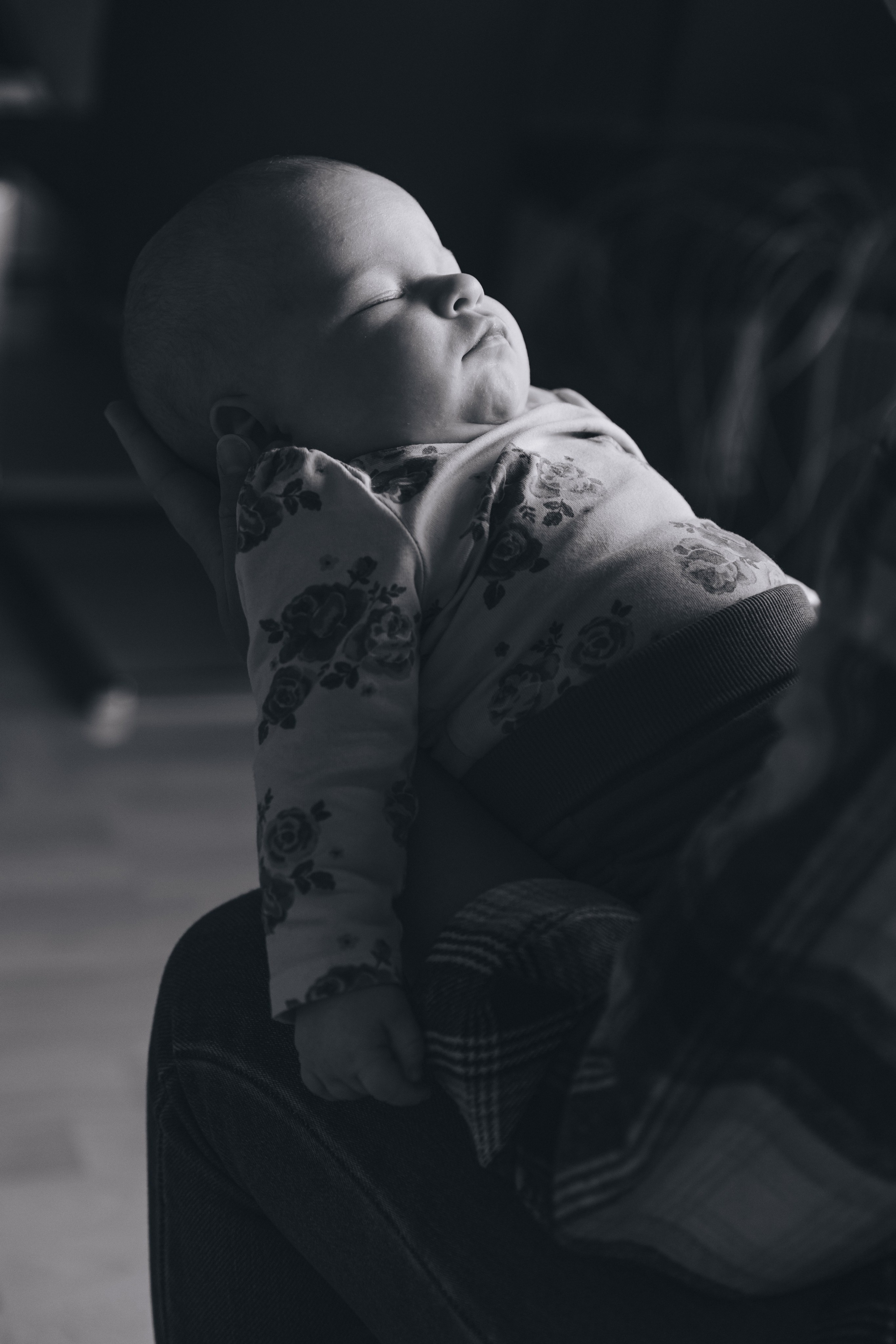 Baby schläft friedlich auf dem Arm der Mutter.