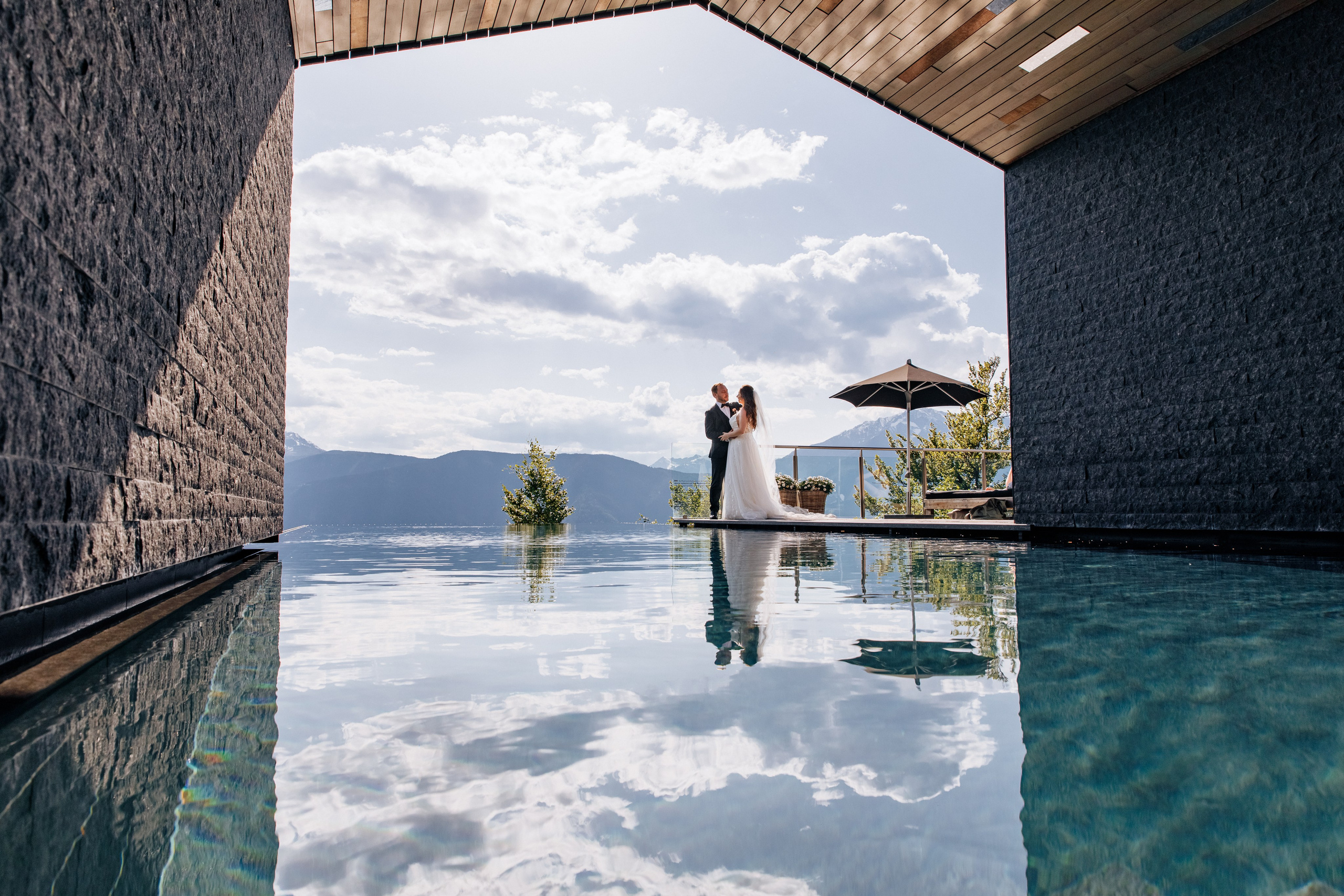 Braut und Bräutigam stehen verliebt am Pool des Miramonti Boutique Hotels in Südtirol – ihre Spiegelung im Wasser fängt den magischen Hochzeitsmoment ein.