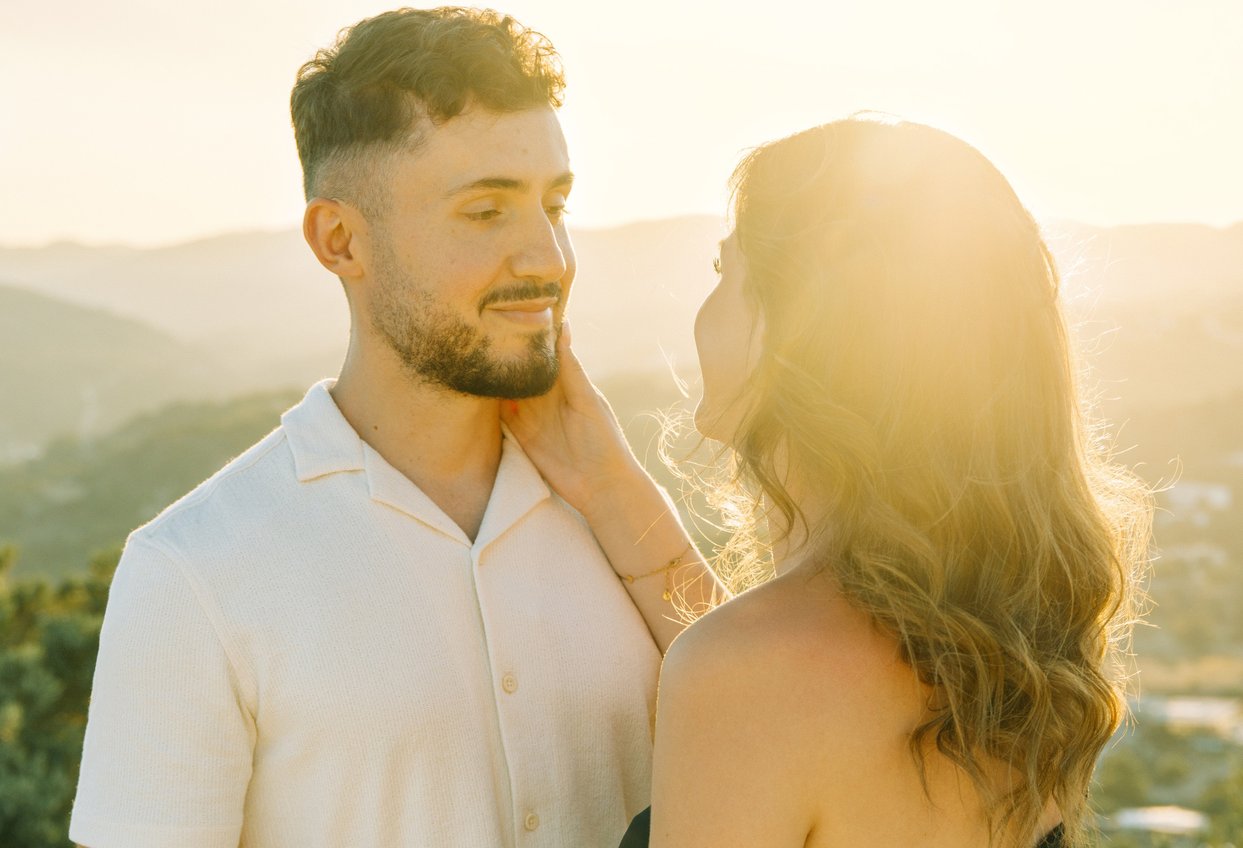 "Liebevoller Blickkontakt: Ein Paar auf dem Felsplateau des Profitis Ilias vor der Kulisse von Faliraki und dem Mittelmeer."