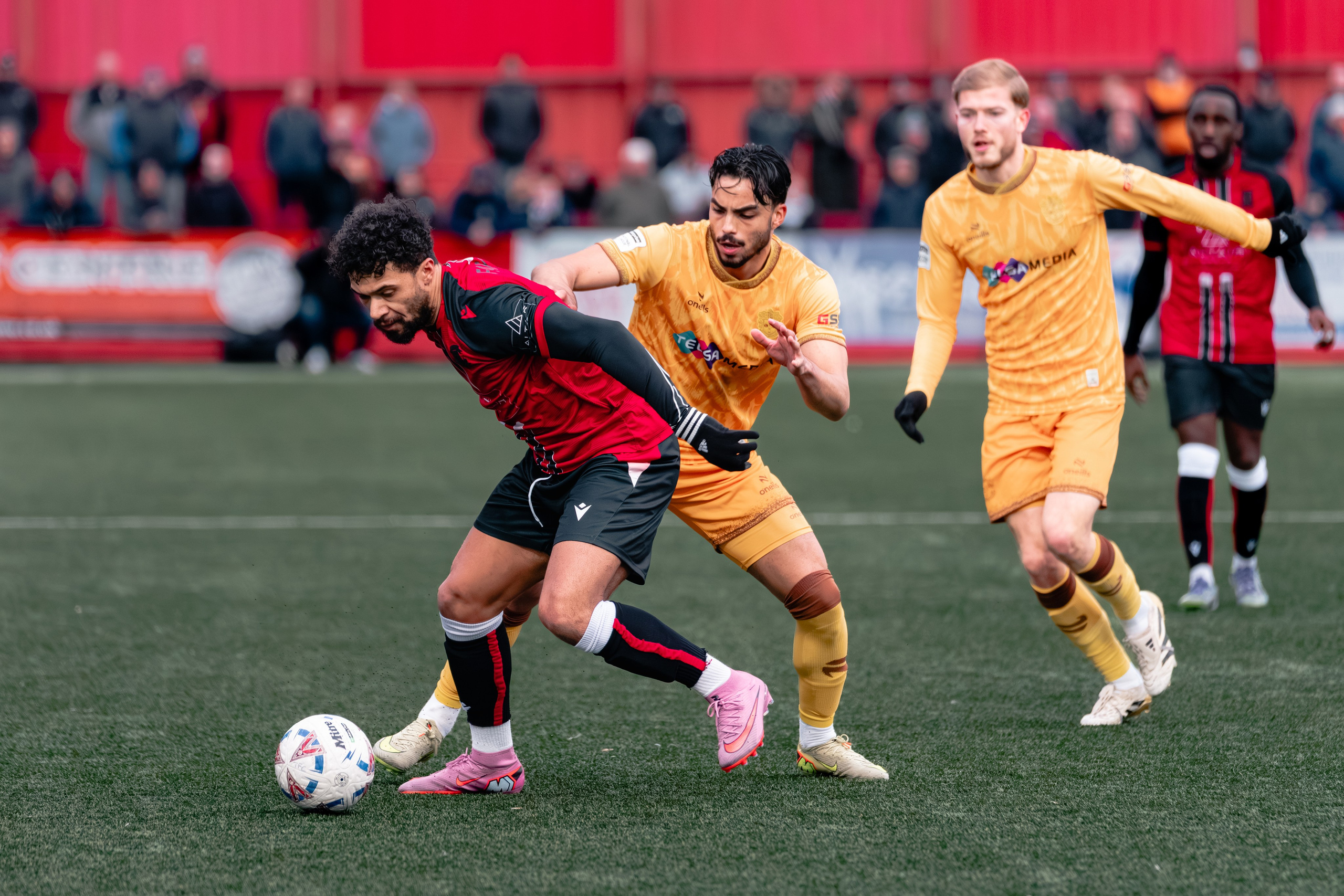 Tamworth’s Luke Fairlamb protects the ball while two Sutton United players close him down.