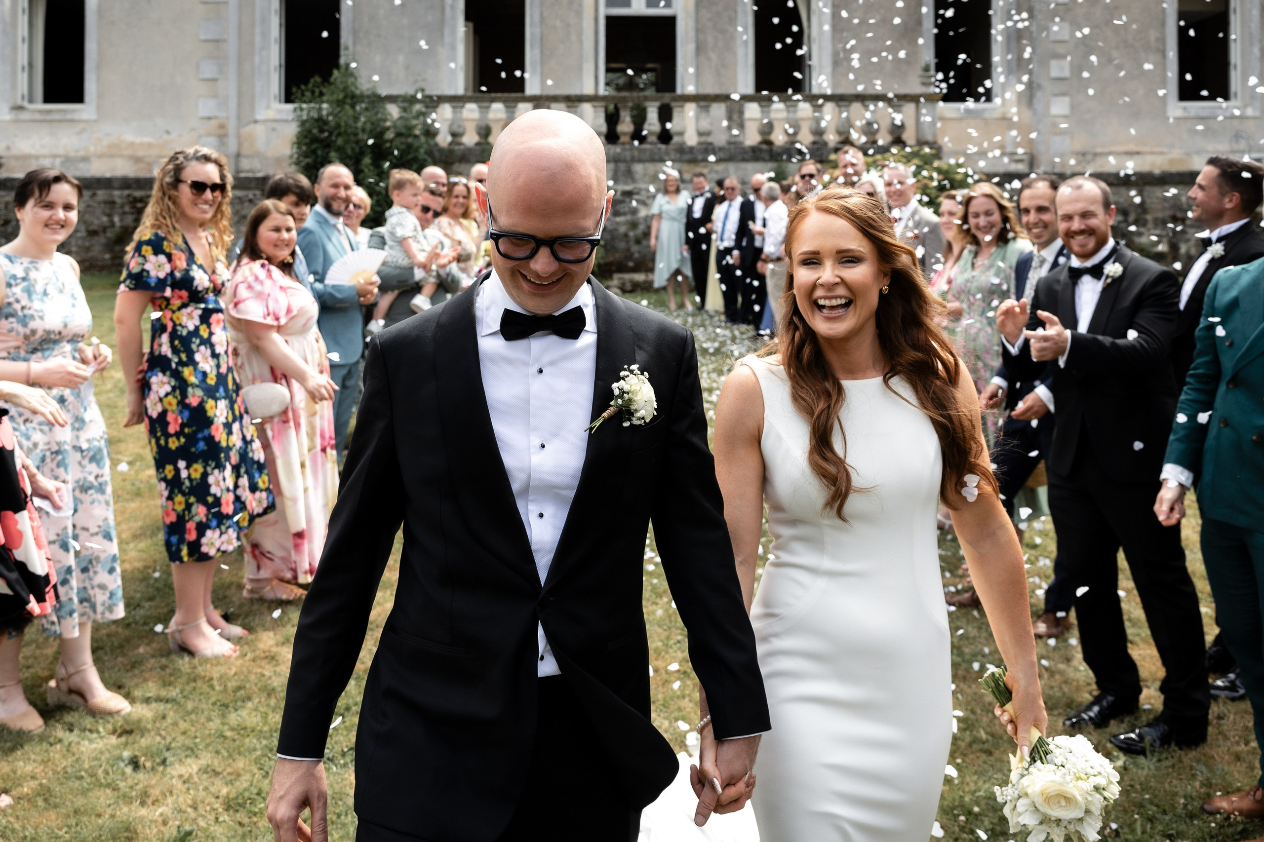 Bride and groom walking through their guests in front of the château
