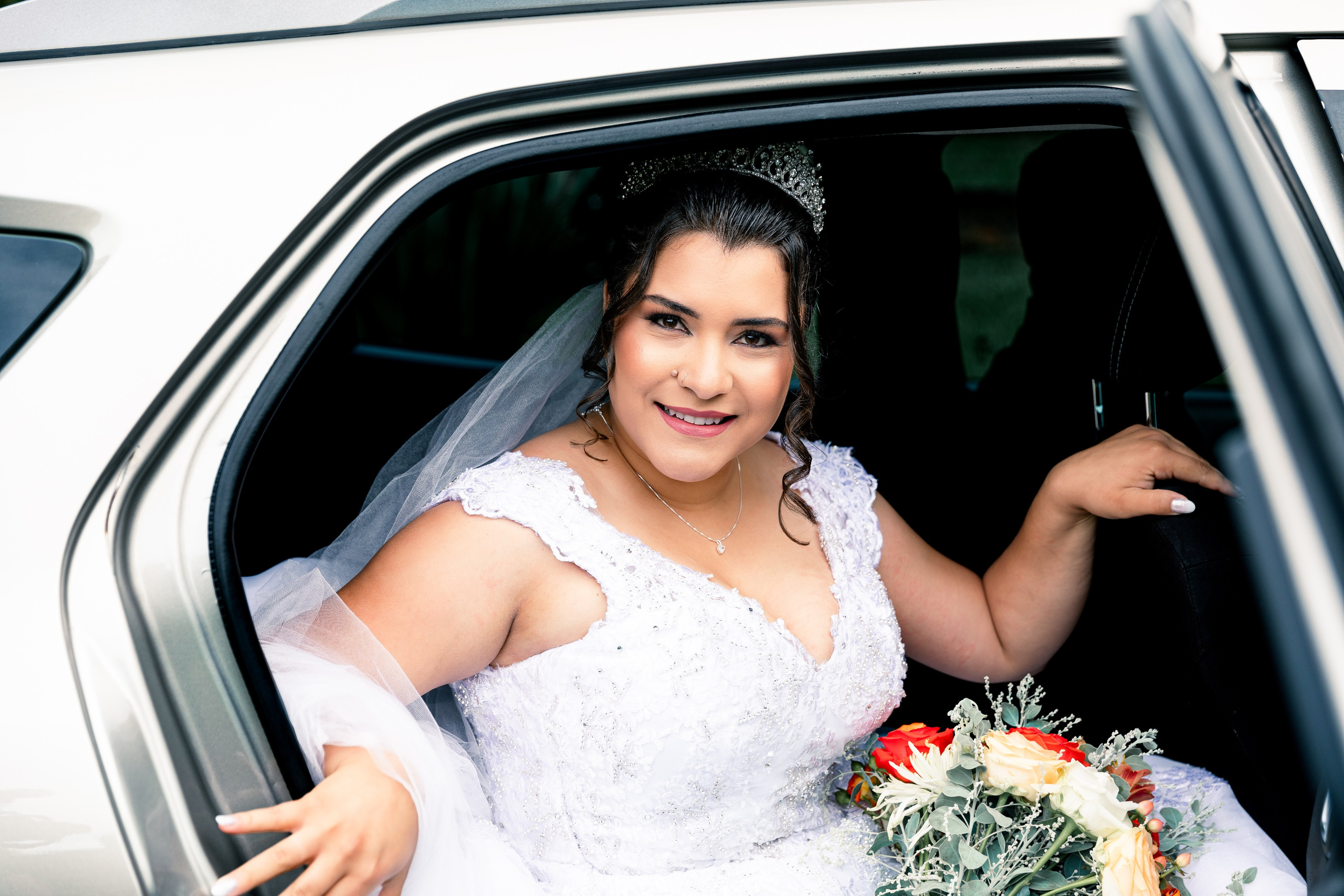 Noiva sorridente saindo do carro com buquê nas mãos, pronta para o grande momento do casamento.
