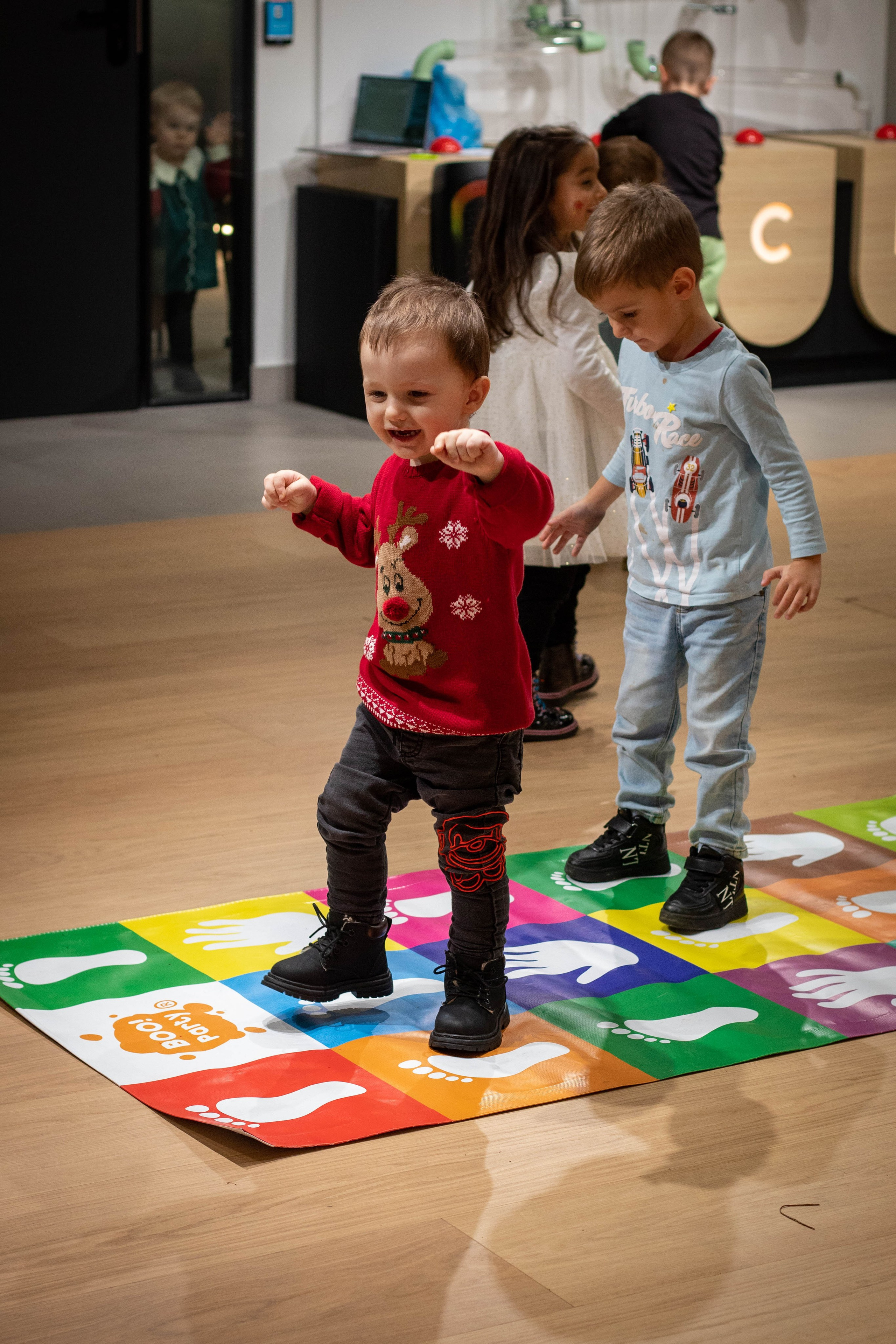 Young child solving a colorful puzzle on the floor of a classroom or play area.