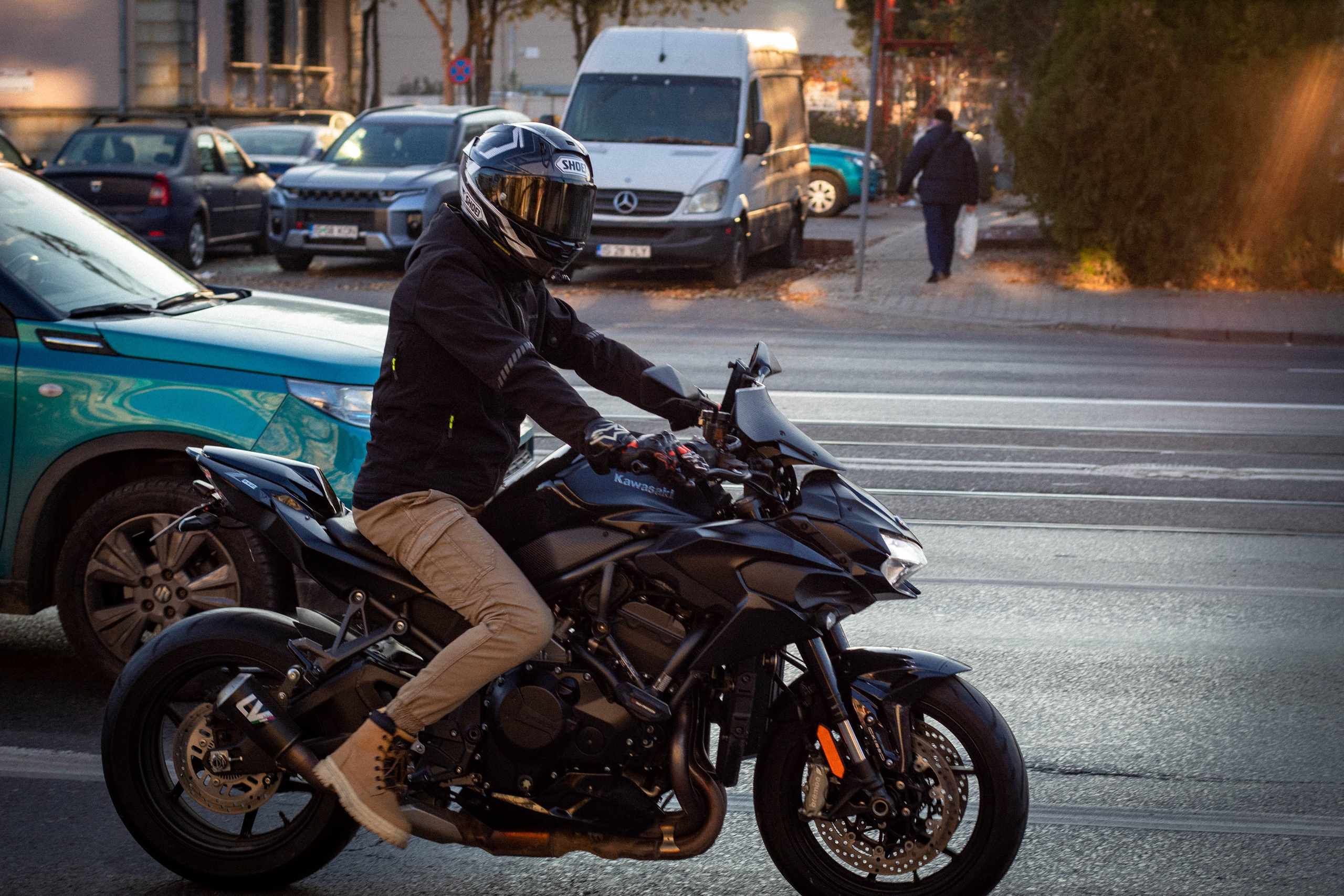 Motorcyclist in full gear riding a sportbike on an urban street at speed.