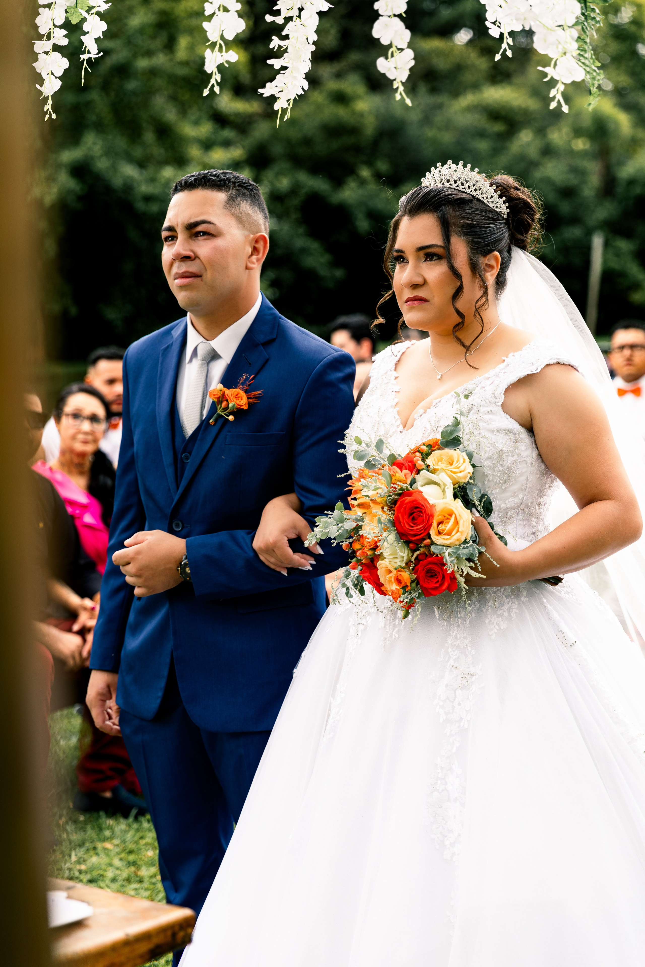 Noiva e noivo de mãos dadas com olhar reflexivo, momento solene da cerimônia.