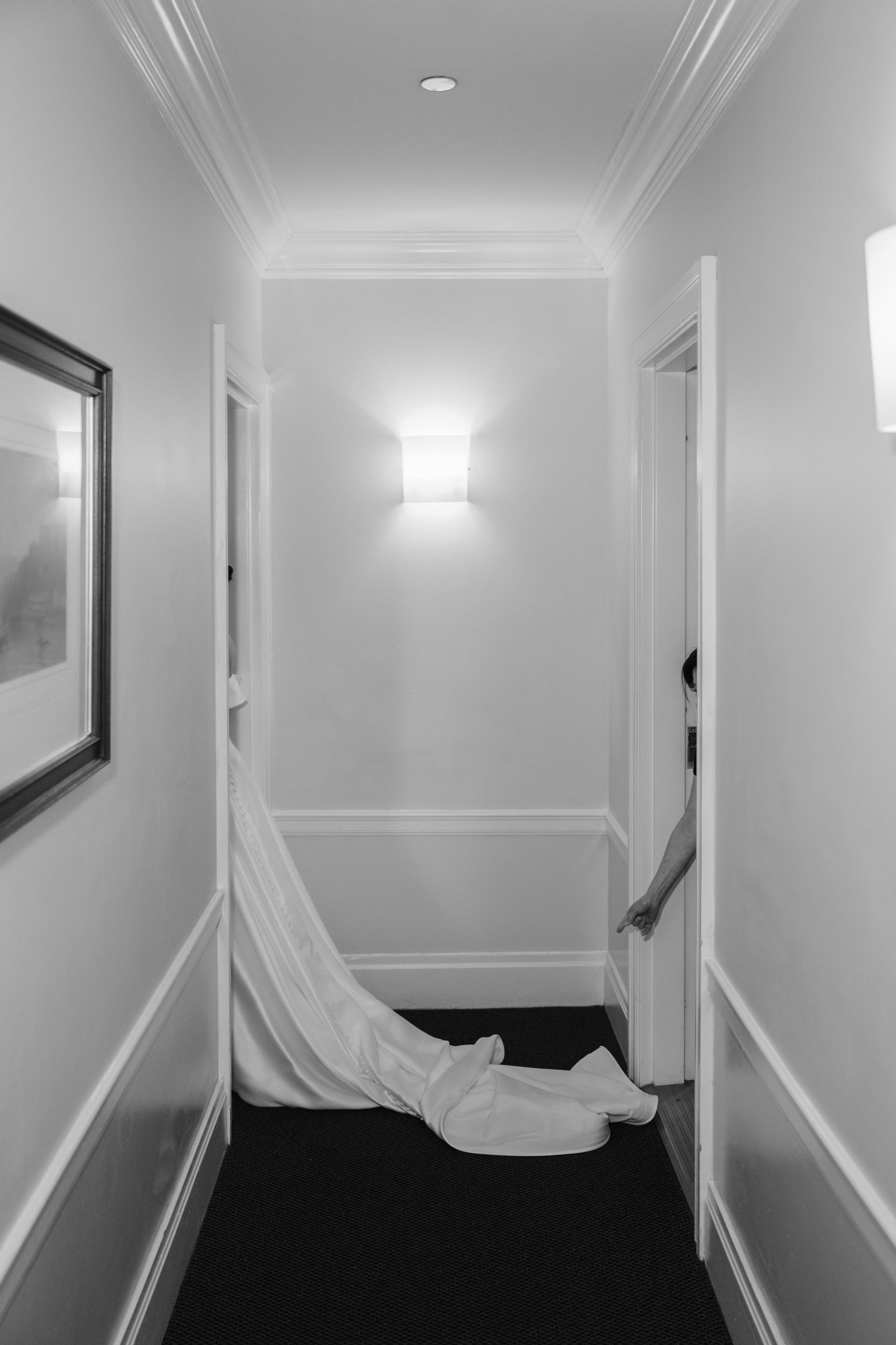 a woman in a white dress is walking down a hallway