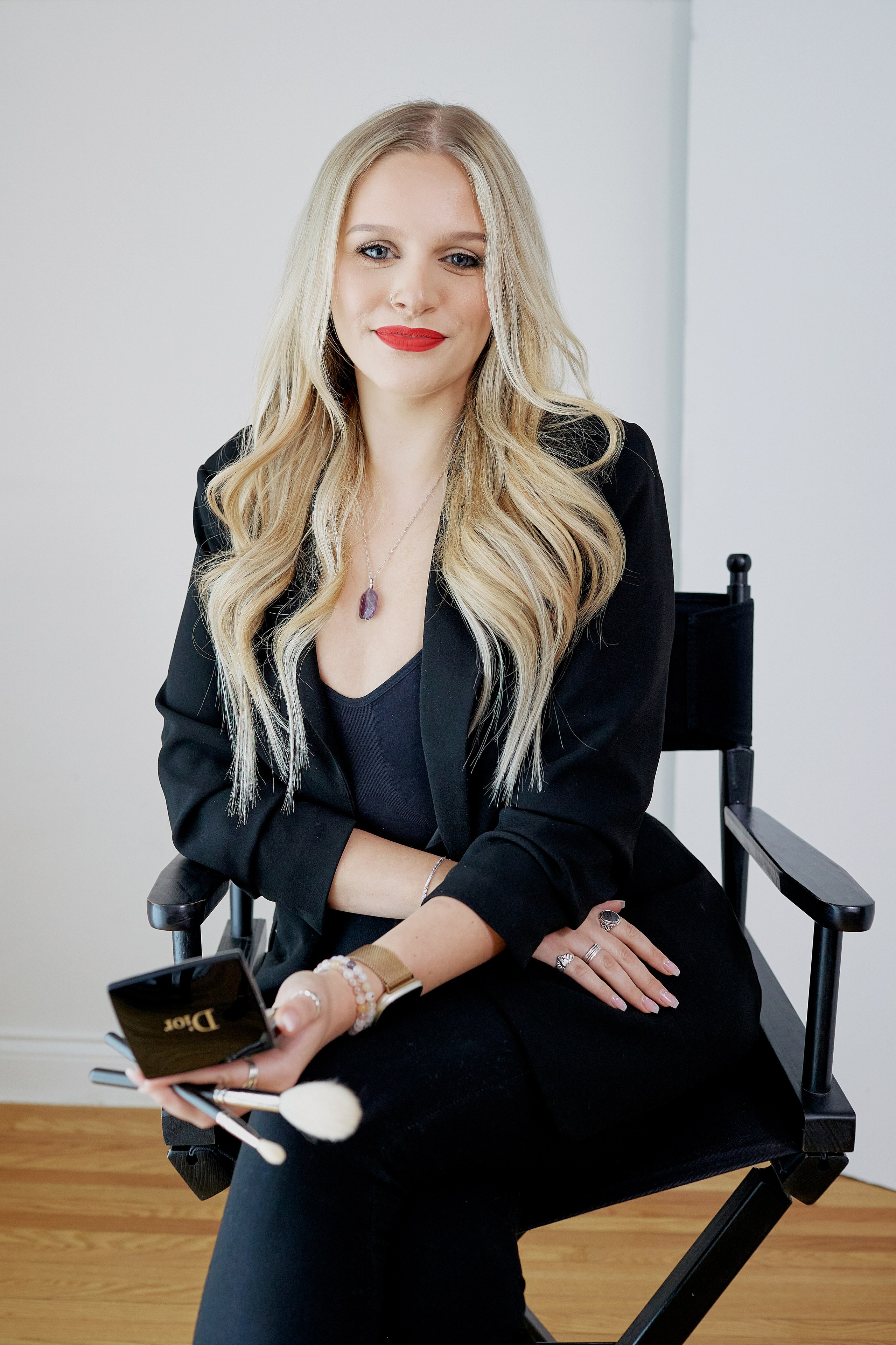 makeup artist sitting in chair holding her makeup tools 