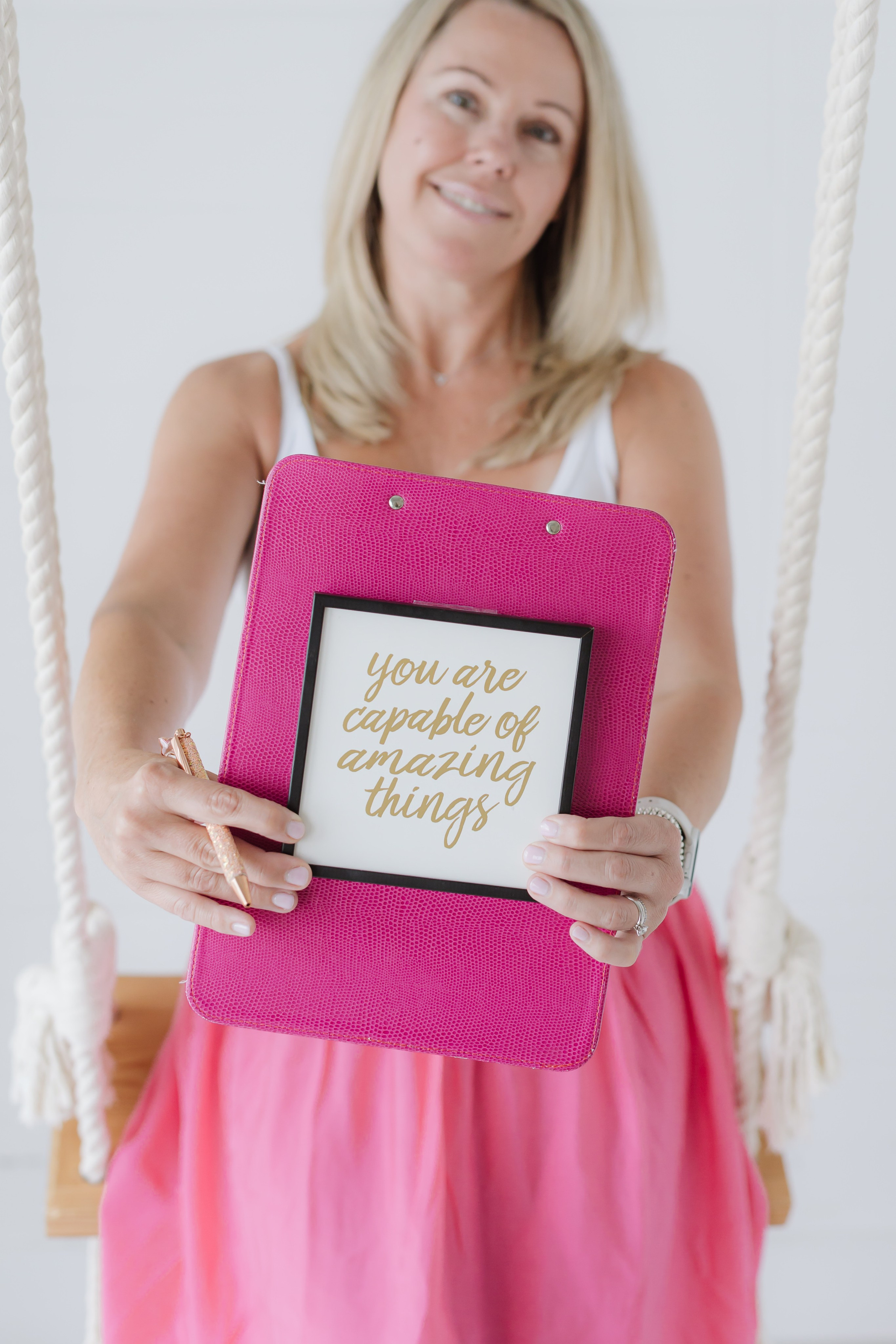 woman in bright pink brand photo holding a motivational sign