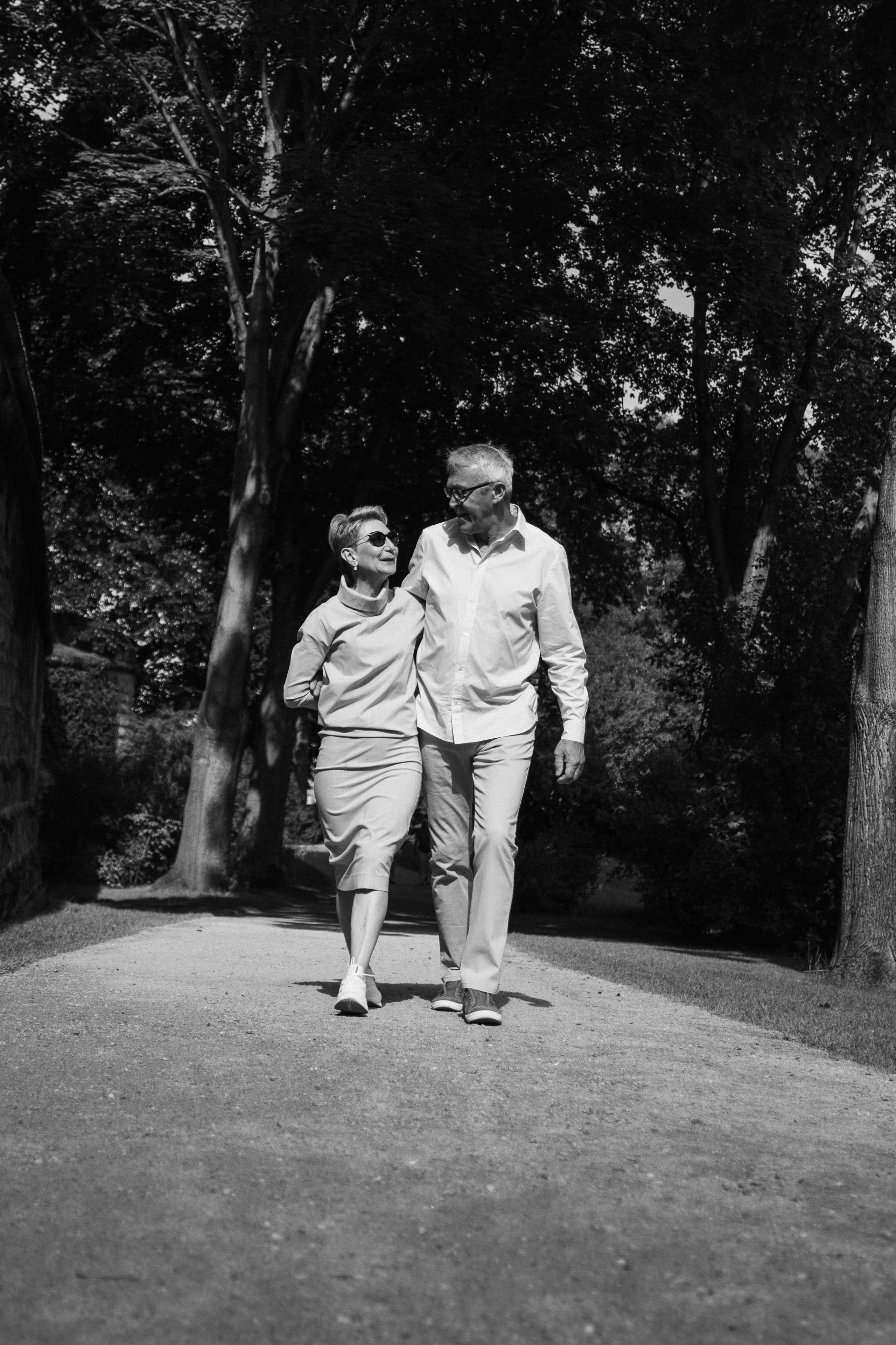 Ein lächelndes Paar spaziert Hand in Hand durch einen Park.