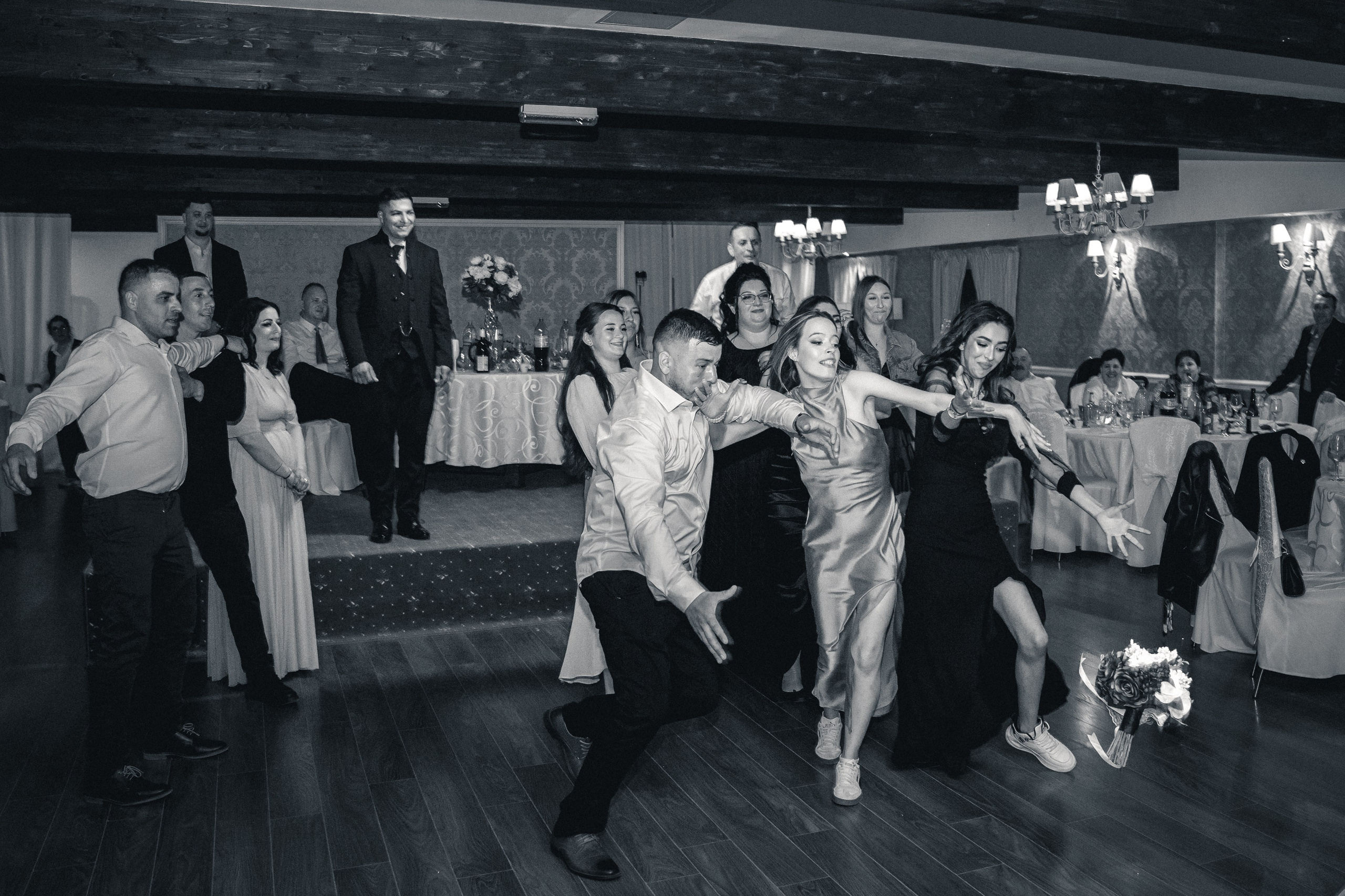 Fotografie haioasă la nuntă, invitați luptându-se pentru buchetul miresei, moment dinamic alb-negru, fotograf evenimente București, incadru.ro.